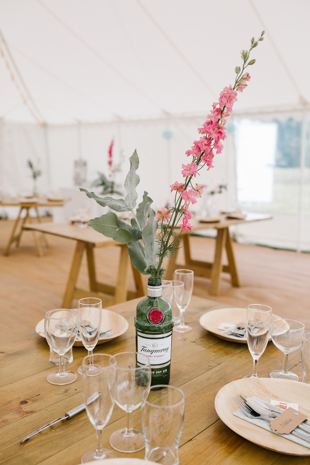 gin bottle holding wild flowers as the table centrepiece at the DIY wedding in the Cotswolds