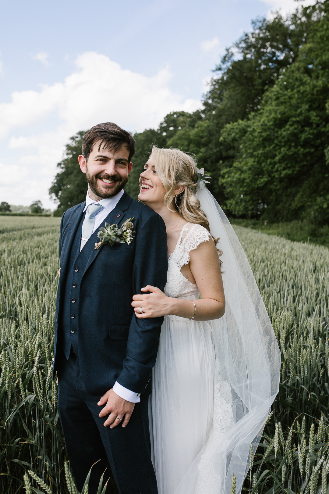 romantic photo of bride and groom laughing together in a field at wildwood bluebell in the cotswolds