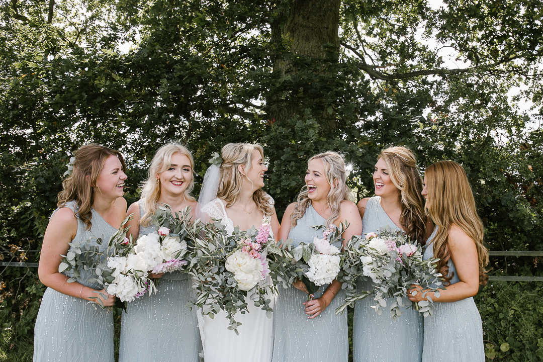 natural and happy photo of bridesmaids laughing together at the summer wedding in the cotswolds- wildwood bluebell wedding photographer