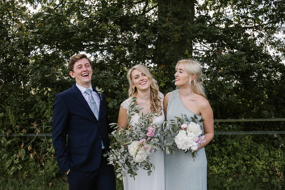 happy photo of bride with brother and sister laughing together in the cotswolds