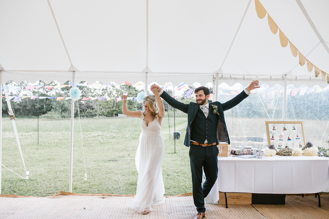 bride and groom celebrating as they enter their marquee wedding venue 