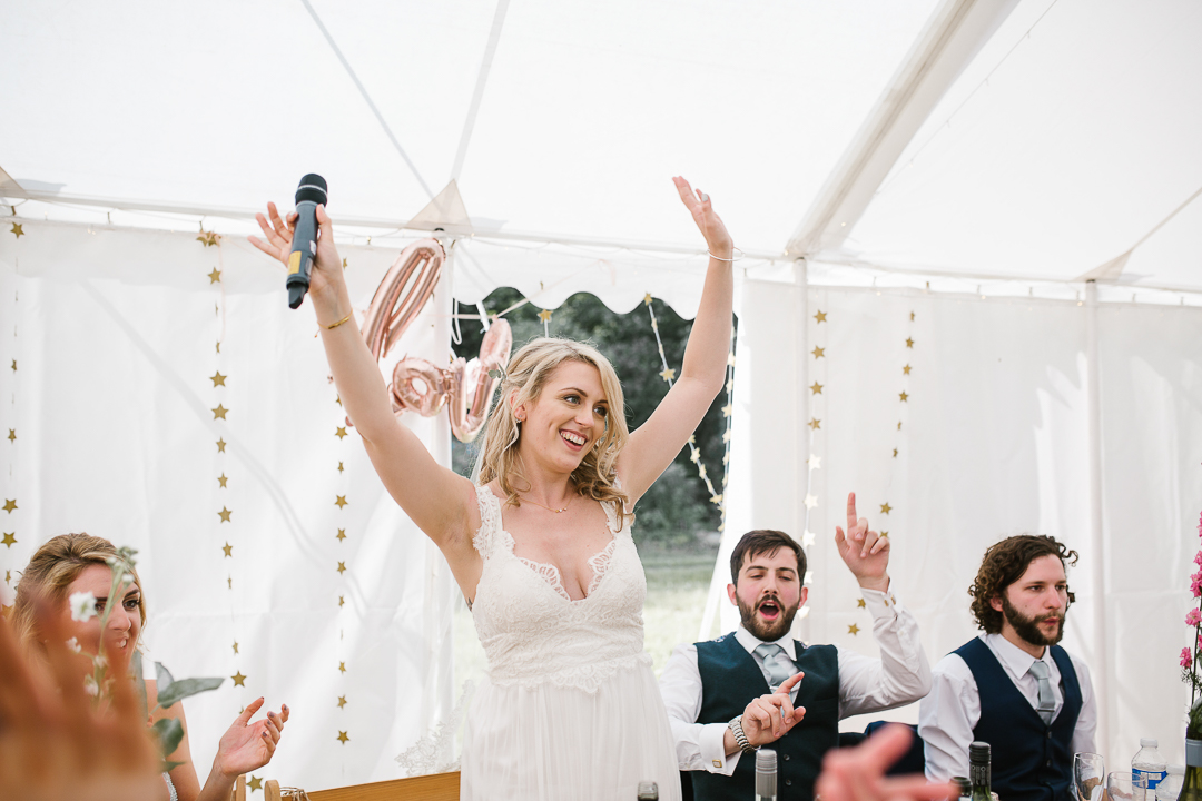 fun photo of bride celebrating doing a brides speech during her festival wedding