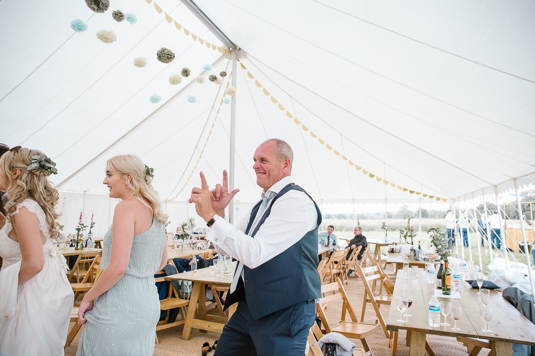 fun photo of father of the bride dancing on the marquee dancefloor at wedding in the cotswolds