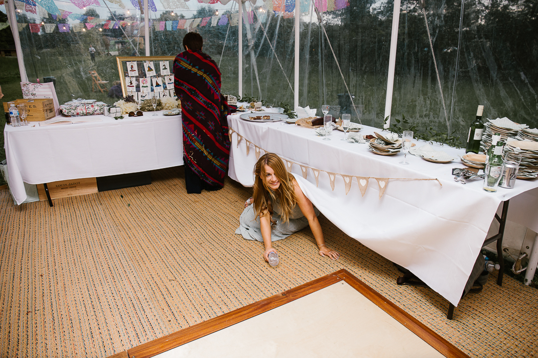 festival wedding, as a bridesmaid crawls drunk under the table at the wedding reception