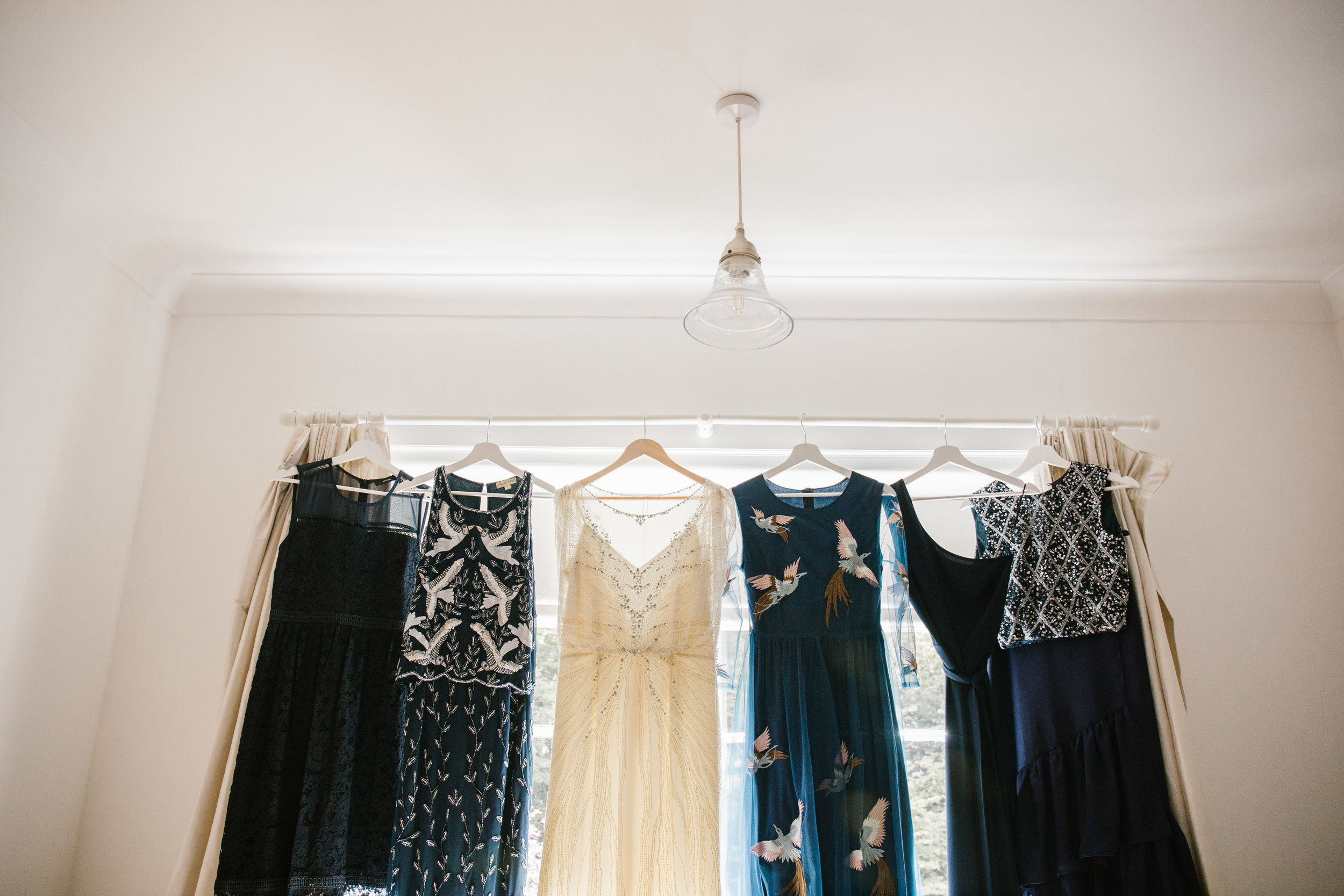 jenny packham wedding dress hanging with navy blue bridesmaids dresses