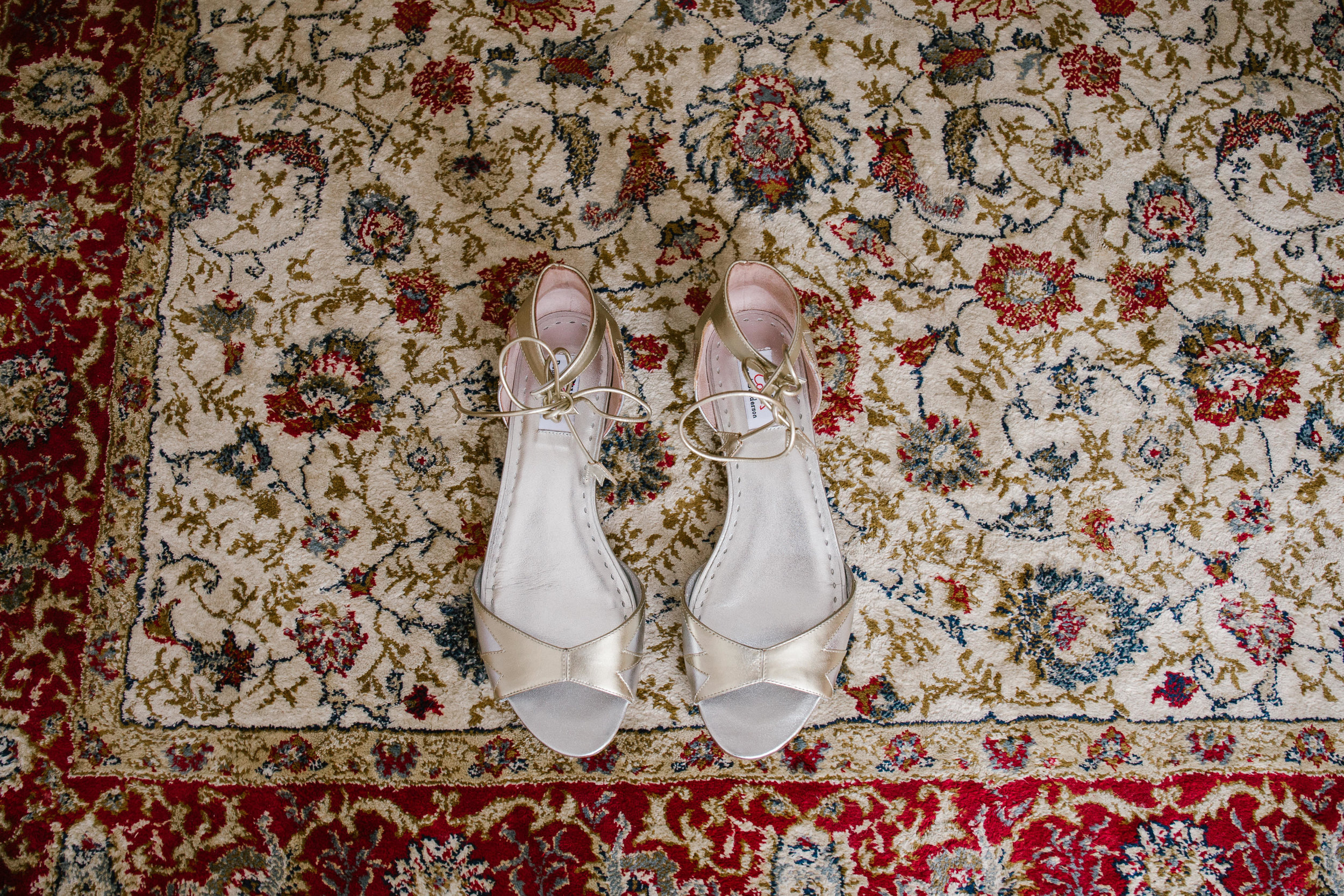 dune wedding shoes on a patterned carpet in a cottage