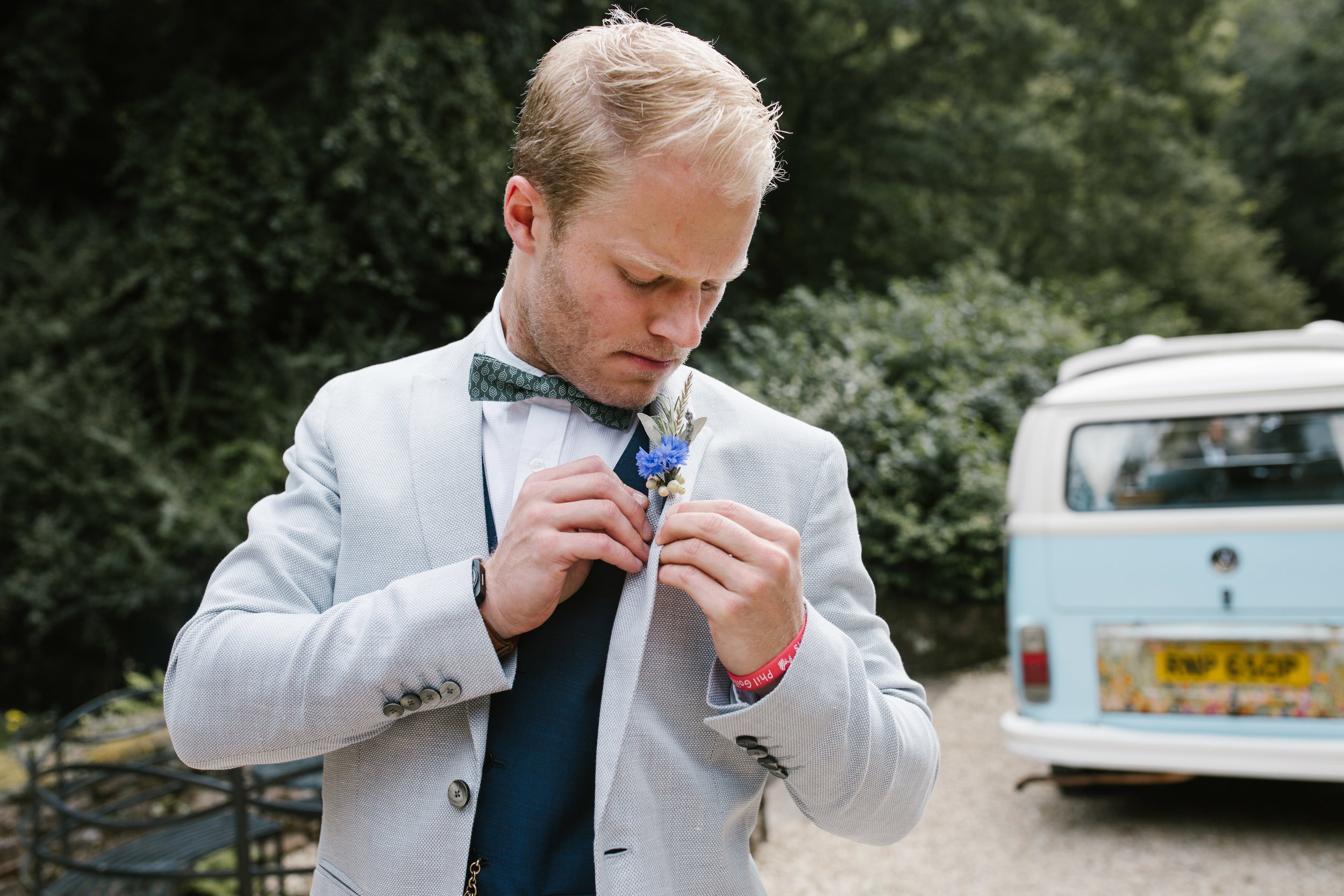 groom wearing reiss suit putting on his wild flower buttonhole