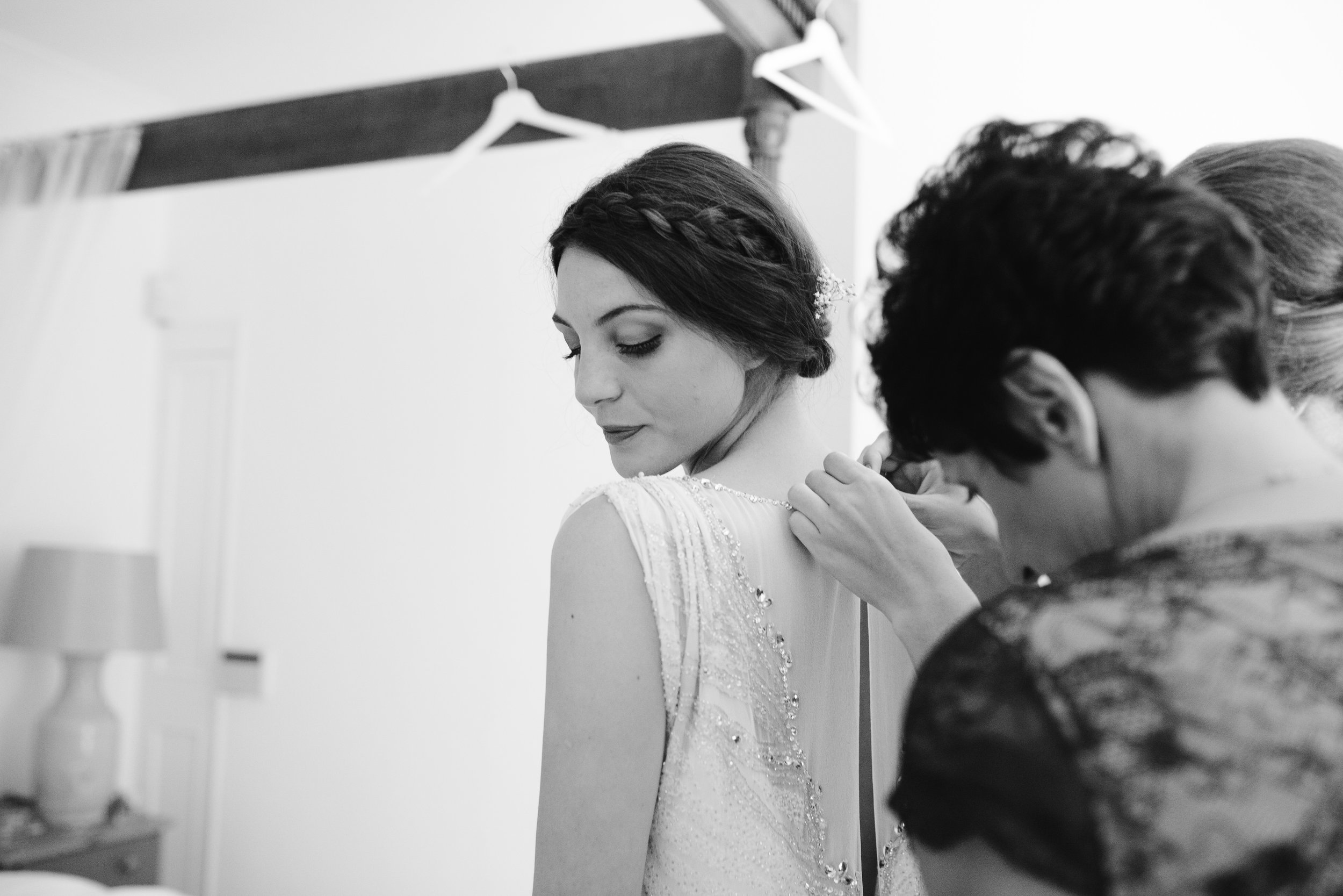 black and white photo of mother of the bride zipping up the jenny packham gown
