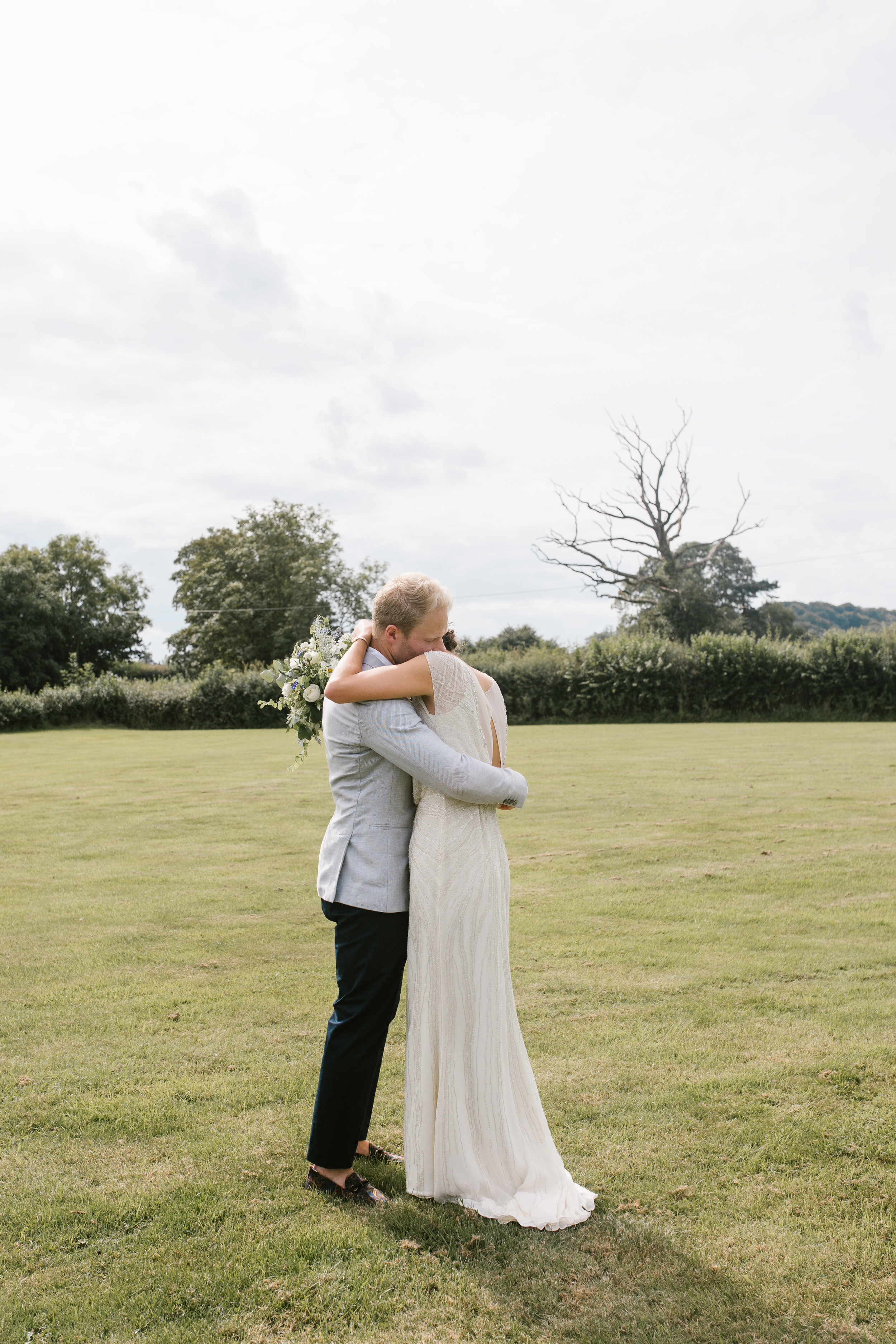 natural photo of bride and groom hugging after their outdoor wedding ceremony