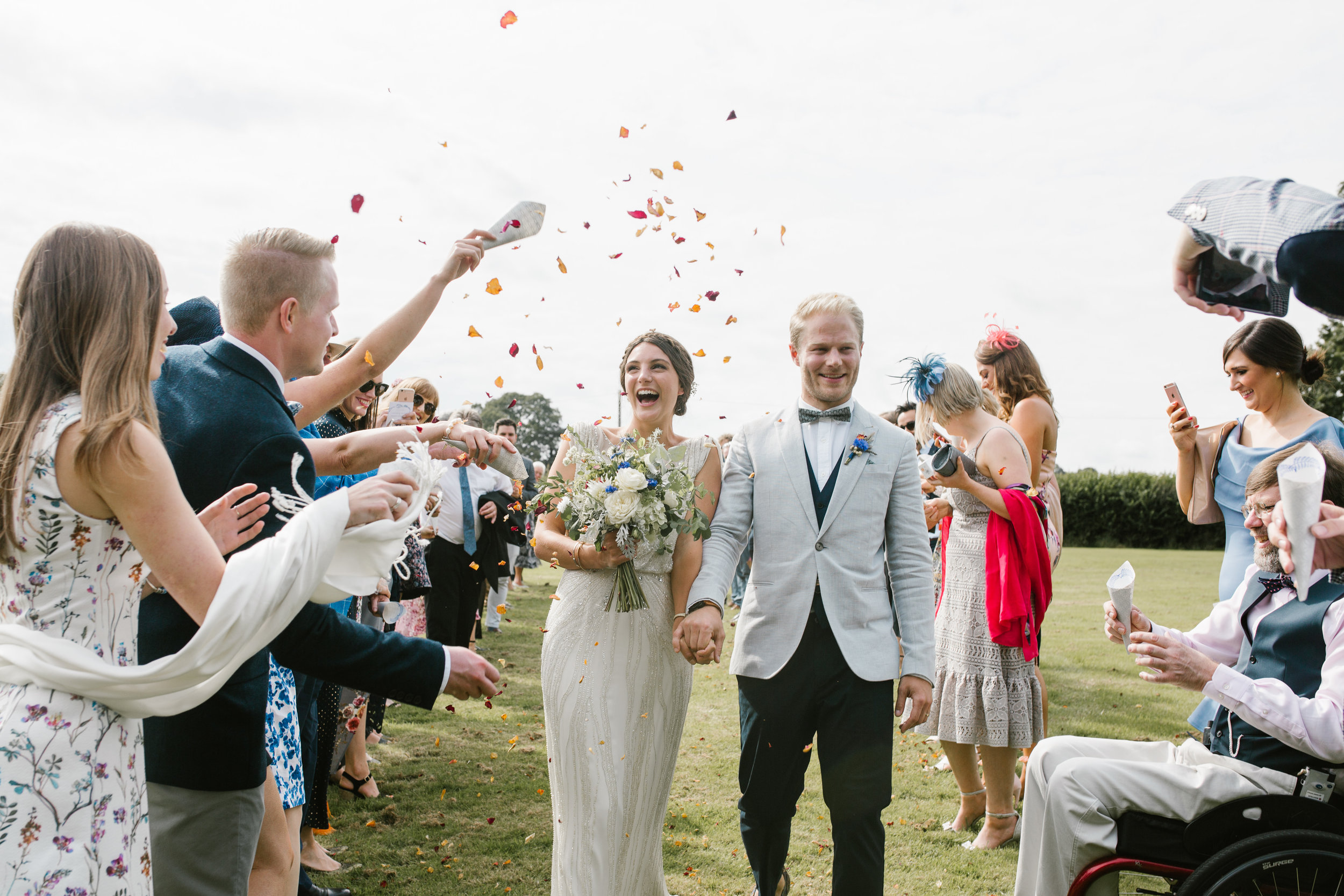 boho brode and groom being showered in confetti after their outdoor wedding