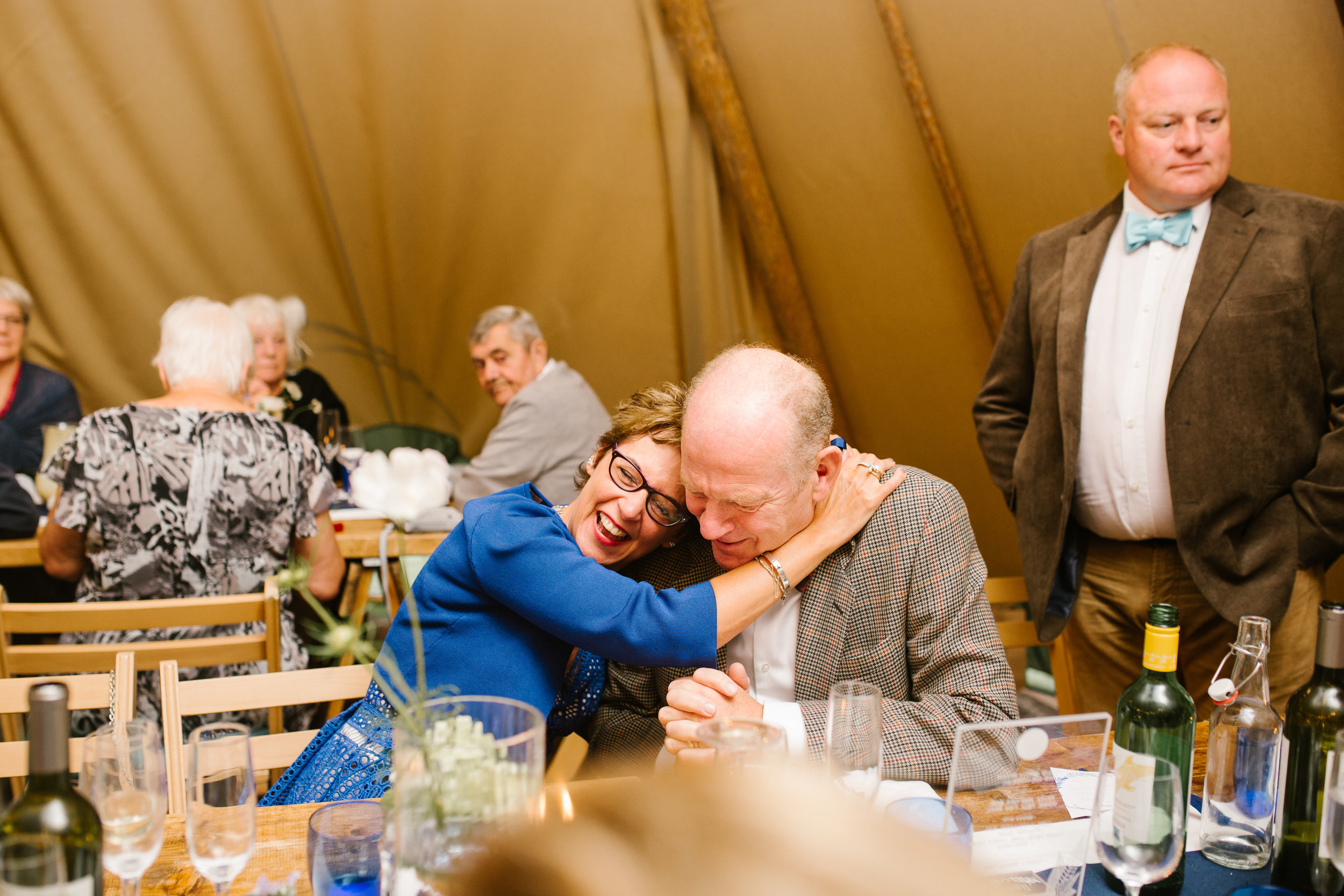 natural photo of wedding guests hugging one another during the wedding speeches