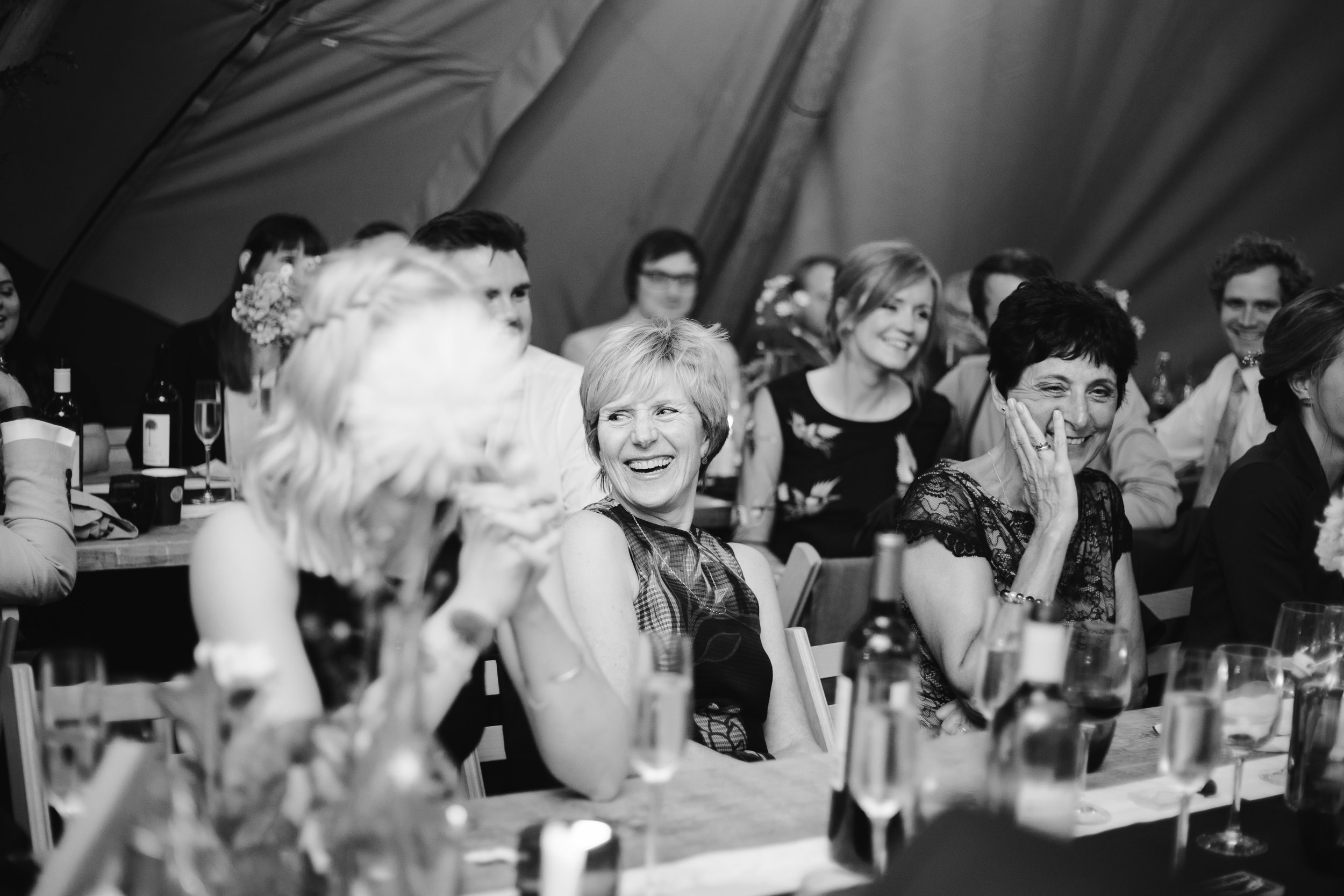 black and white photo of mother of the groom laughing naturally during the wedding speeches