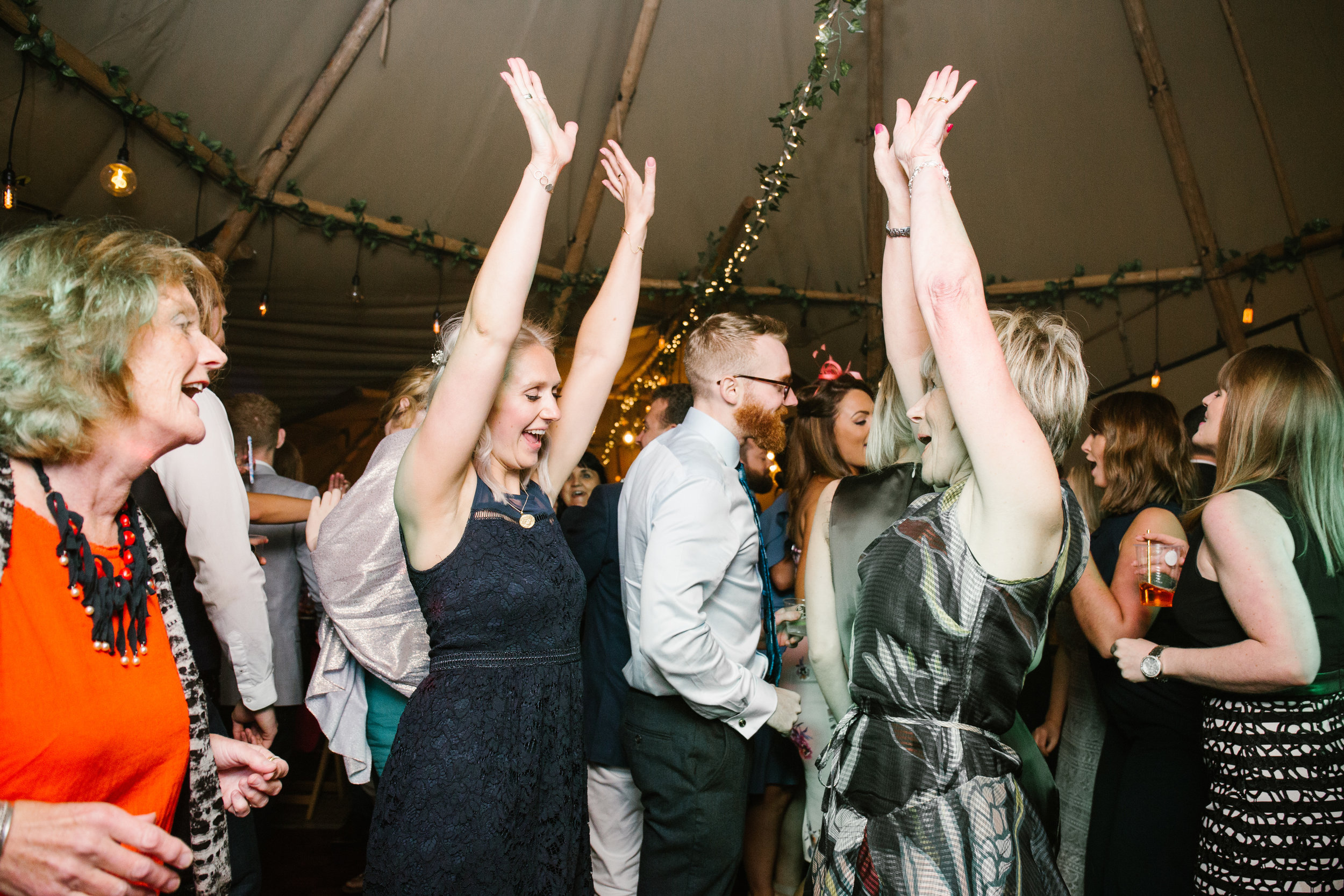 mother and daughter dancing on the dance floor of a wedding with their arms high in the air 