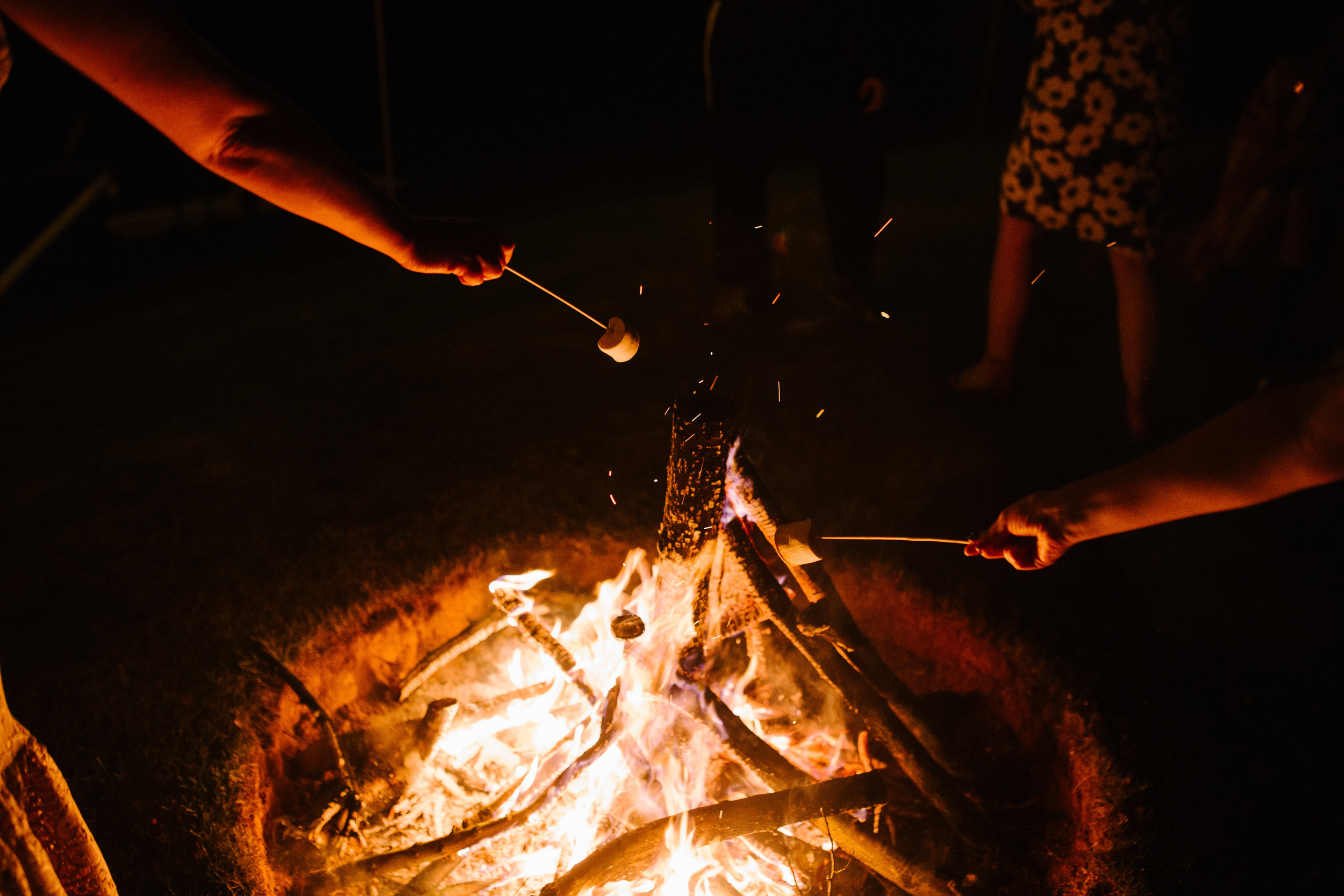 fire pit outside a tipi wedding with guests roasting marshmallows