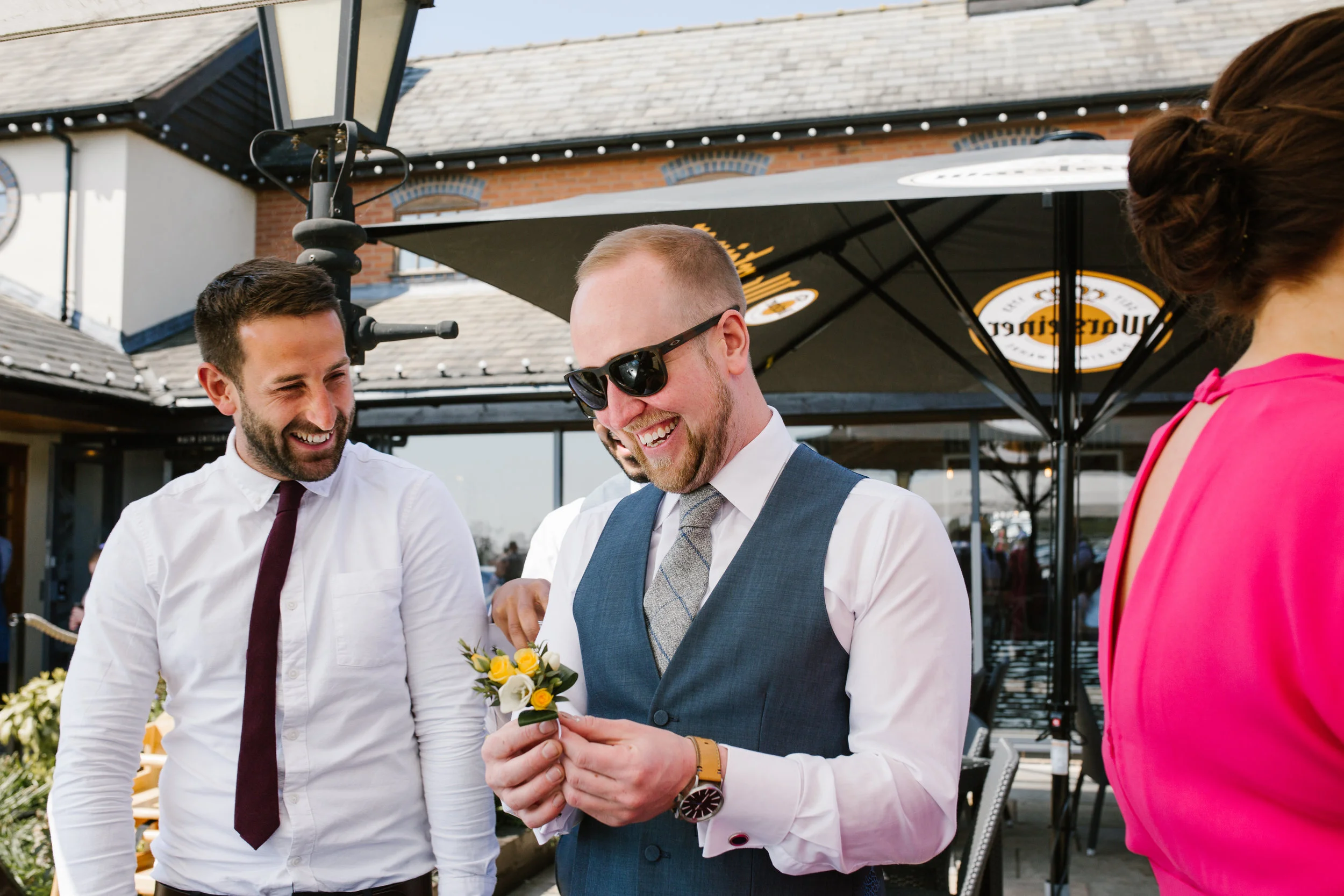 natural photo of groomsmen laughing while attaching their buttonhole