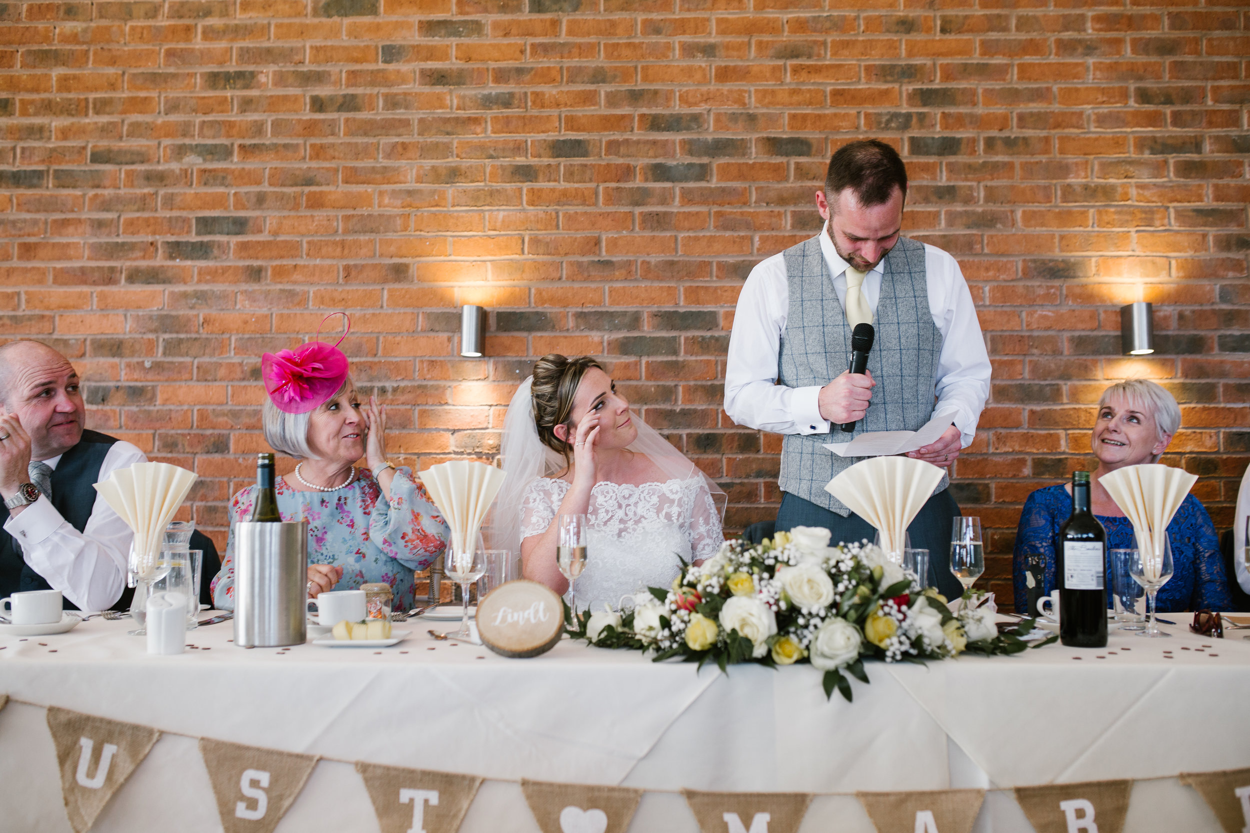 groom reading his speech while his new bride cries