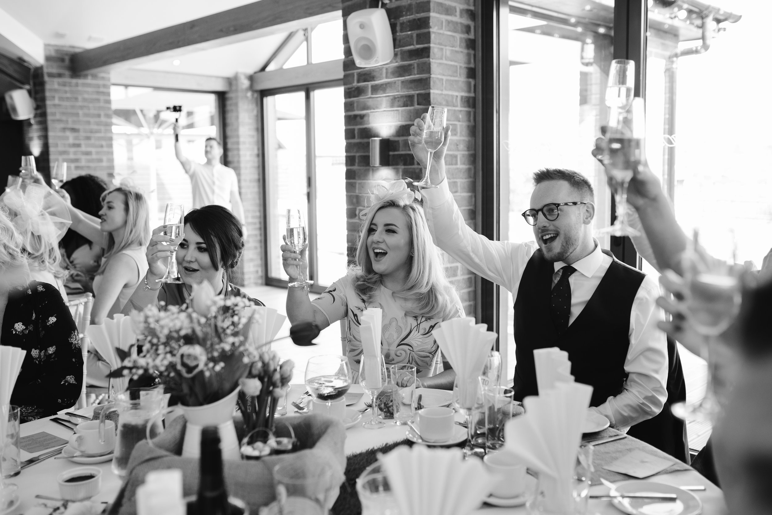 black and white photo of wedding gets cheering during the wedding speeches