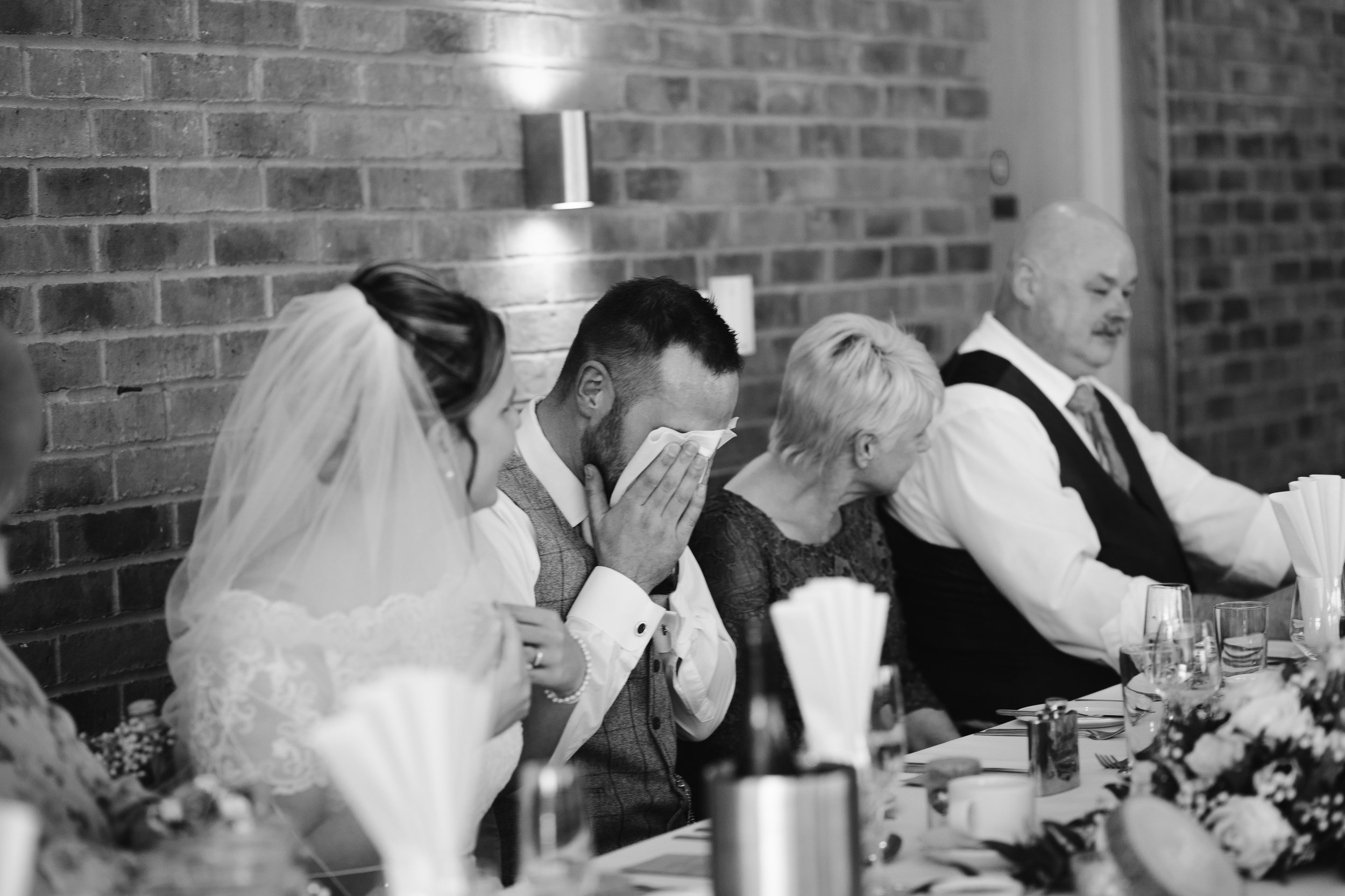 black and white photo of the groom crying during the best man speech 