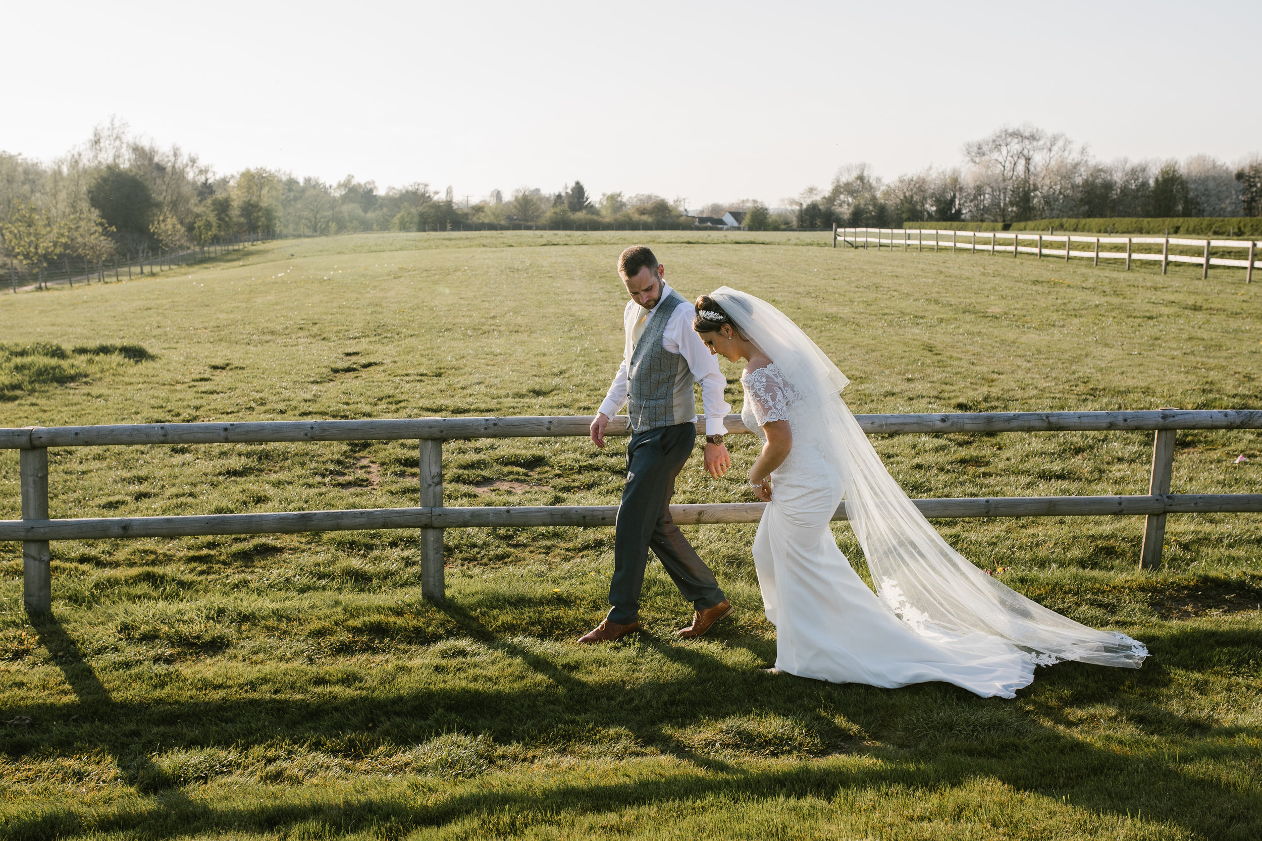 bride and groom strolling through a field together at golden hour