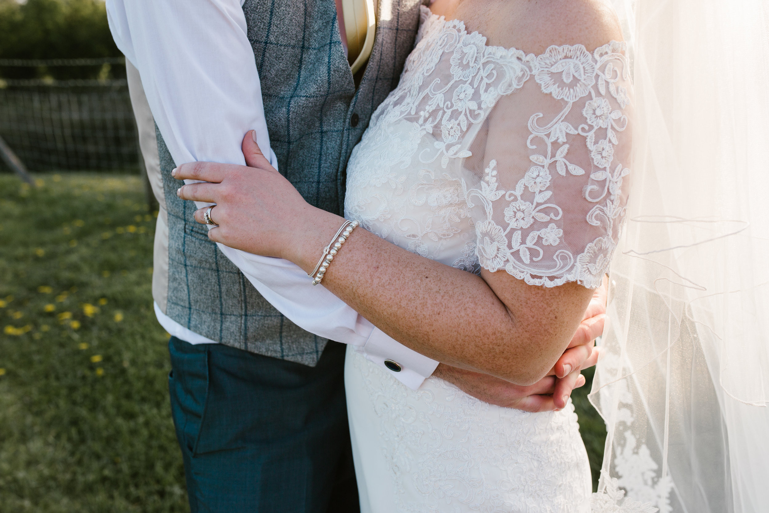 deatil shot of bride and groom holding one another