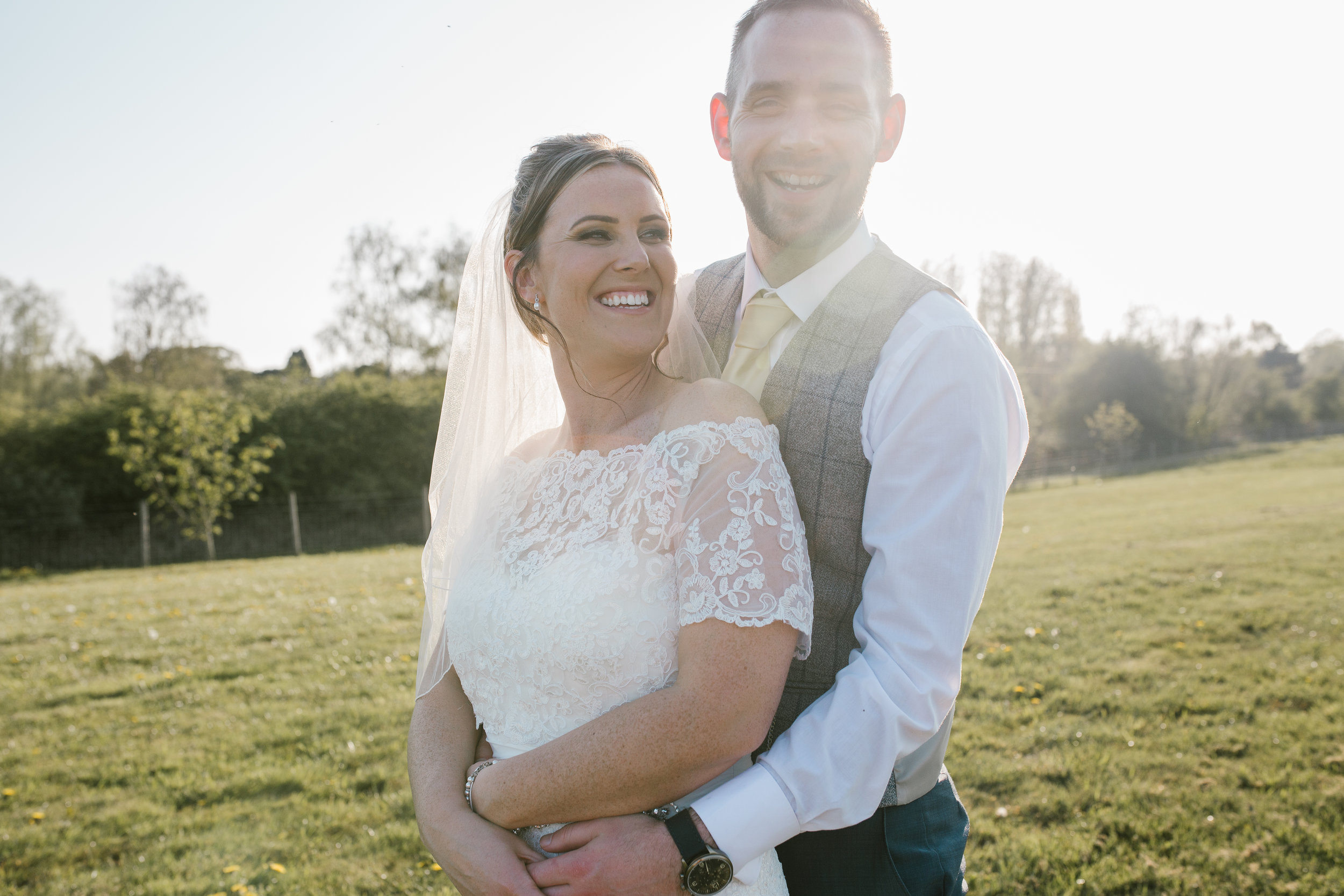 natural happy photo of bride and groom cuddling together laughing at golden hour 