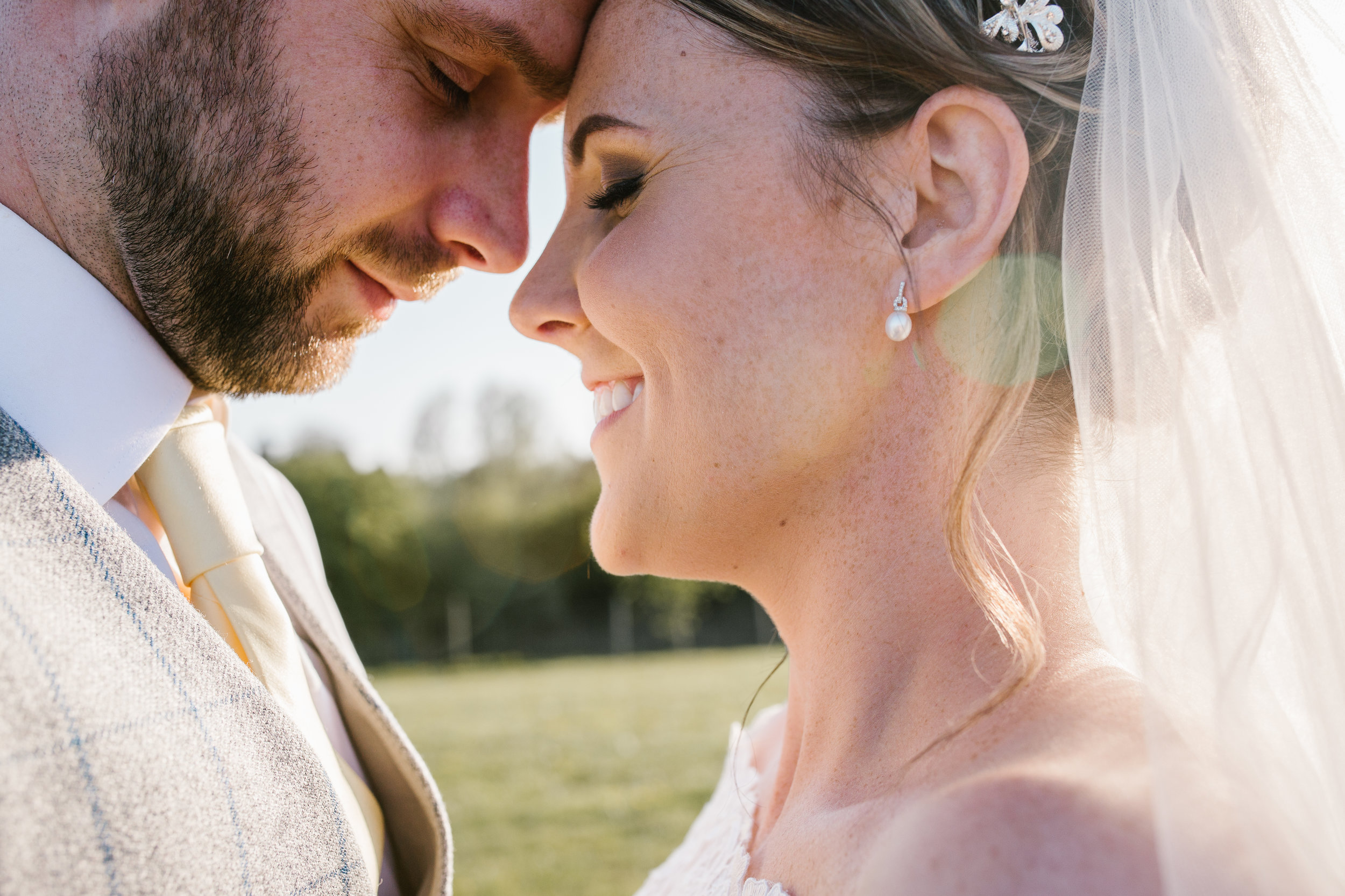 close up photo of bride and groom smiling at one another