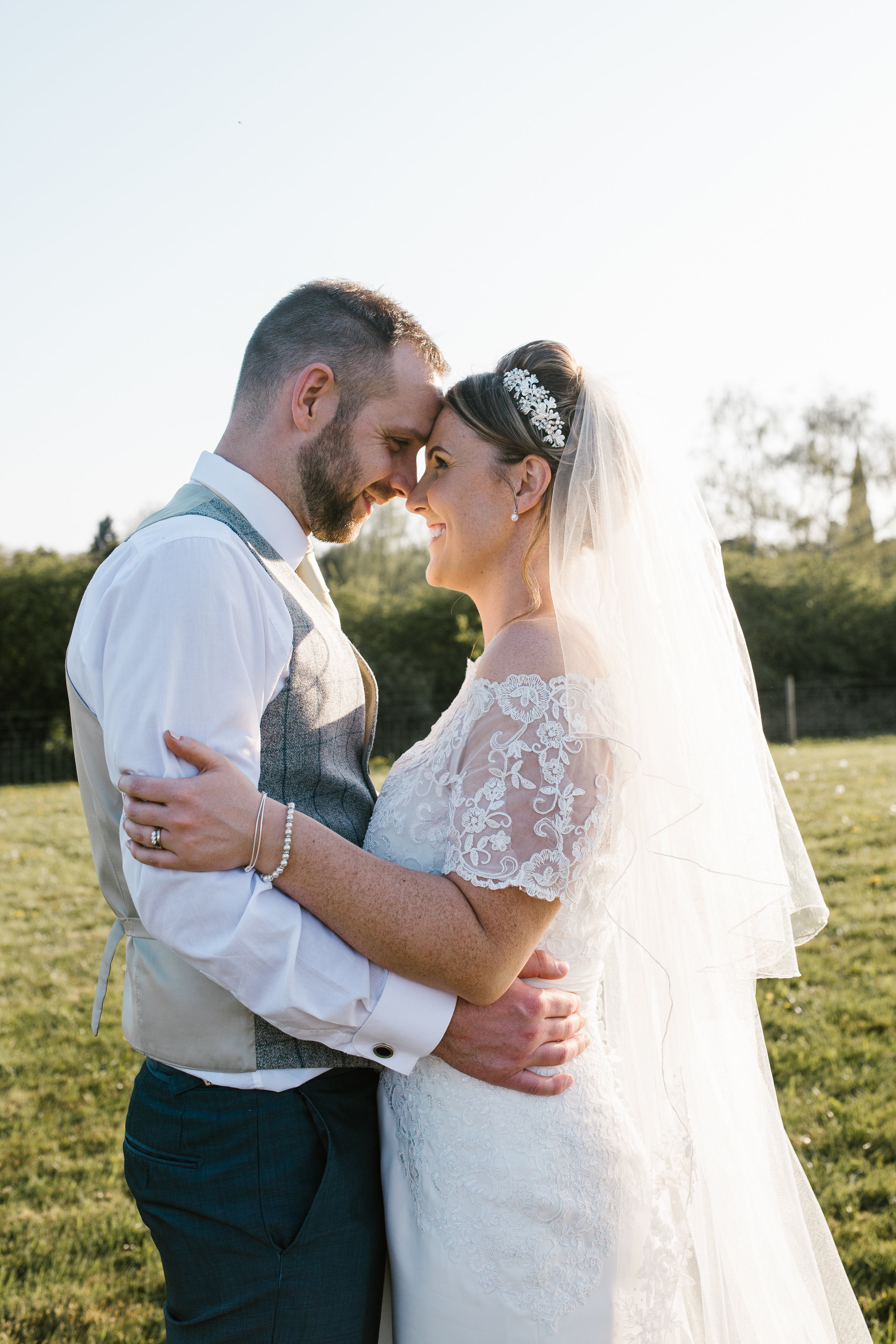 newleyweds standing in a field on the evening of their wedding in the golden sunshine