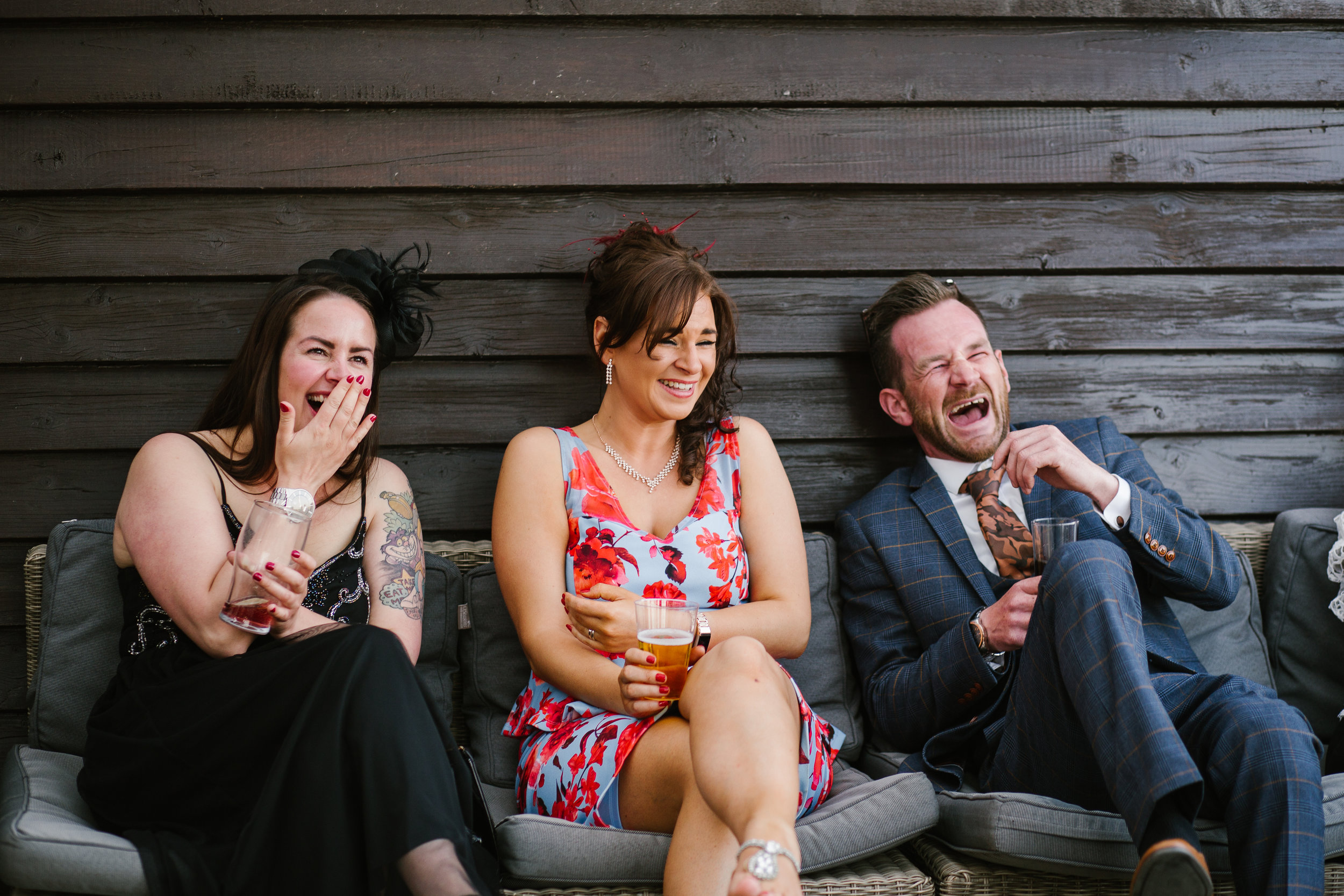 wedding guests laughing together while they have a drink on the patio at the boat house 