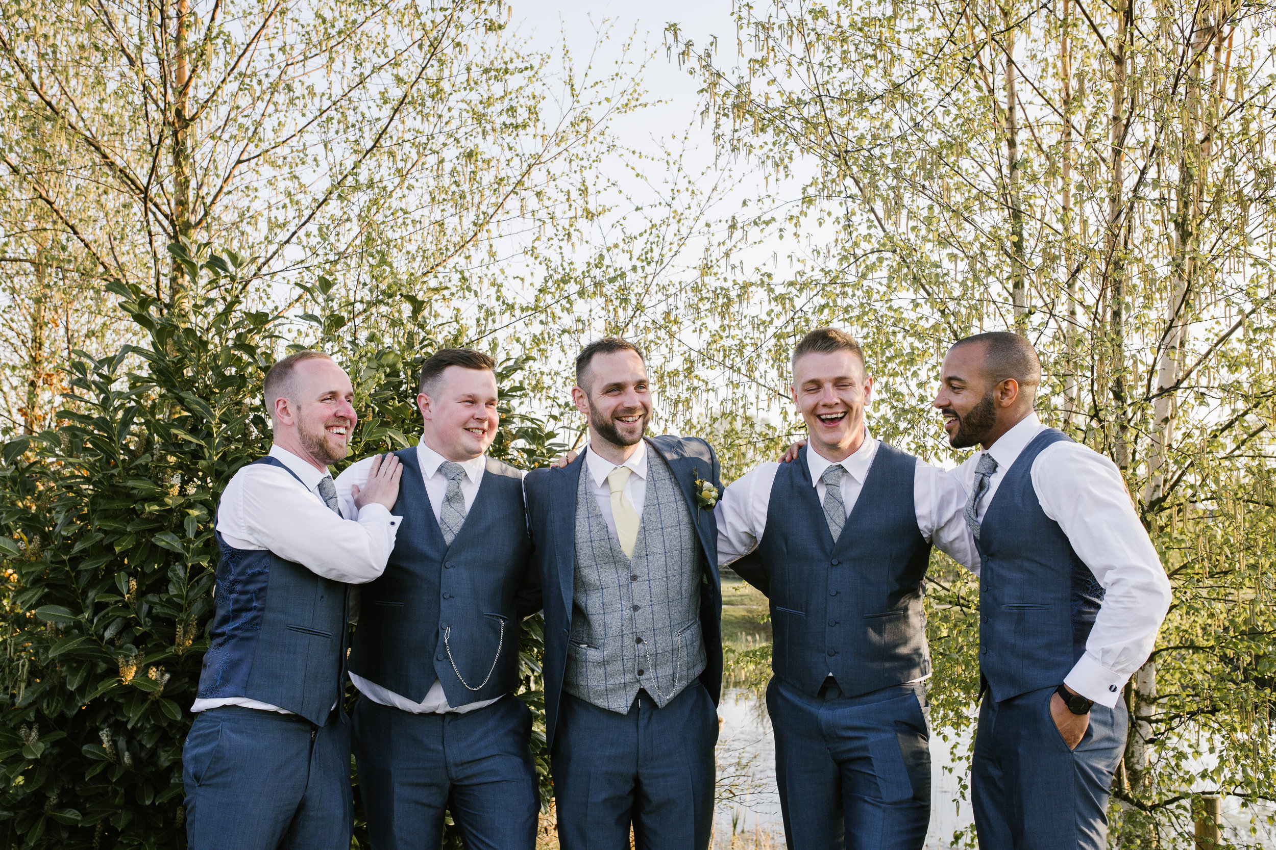 Groom with his groomsmen laughing together at the boat house in aston marina 