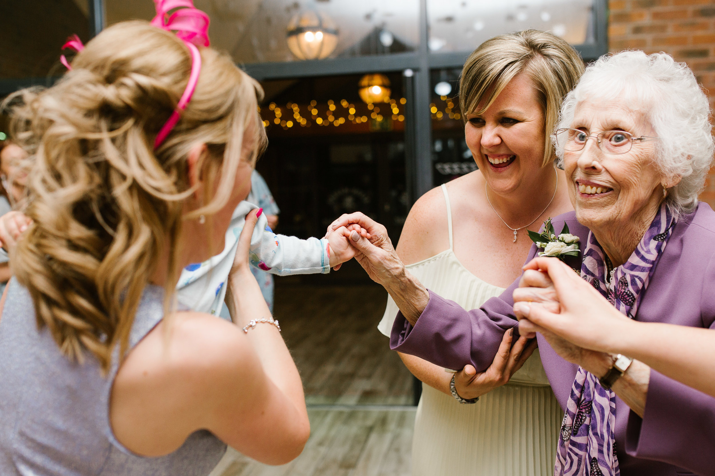 great nan and toddler hold hands together on the dance floor at wedding party at aston marina boat house wedding venue in staffordshire