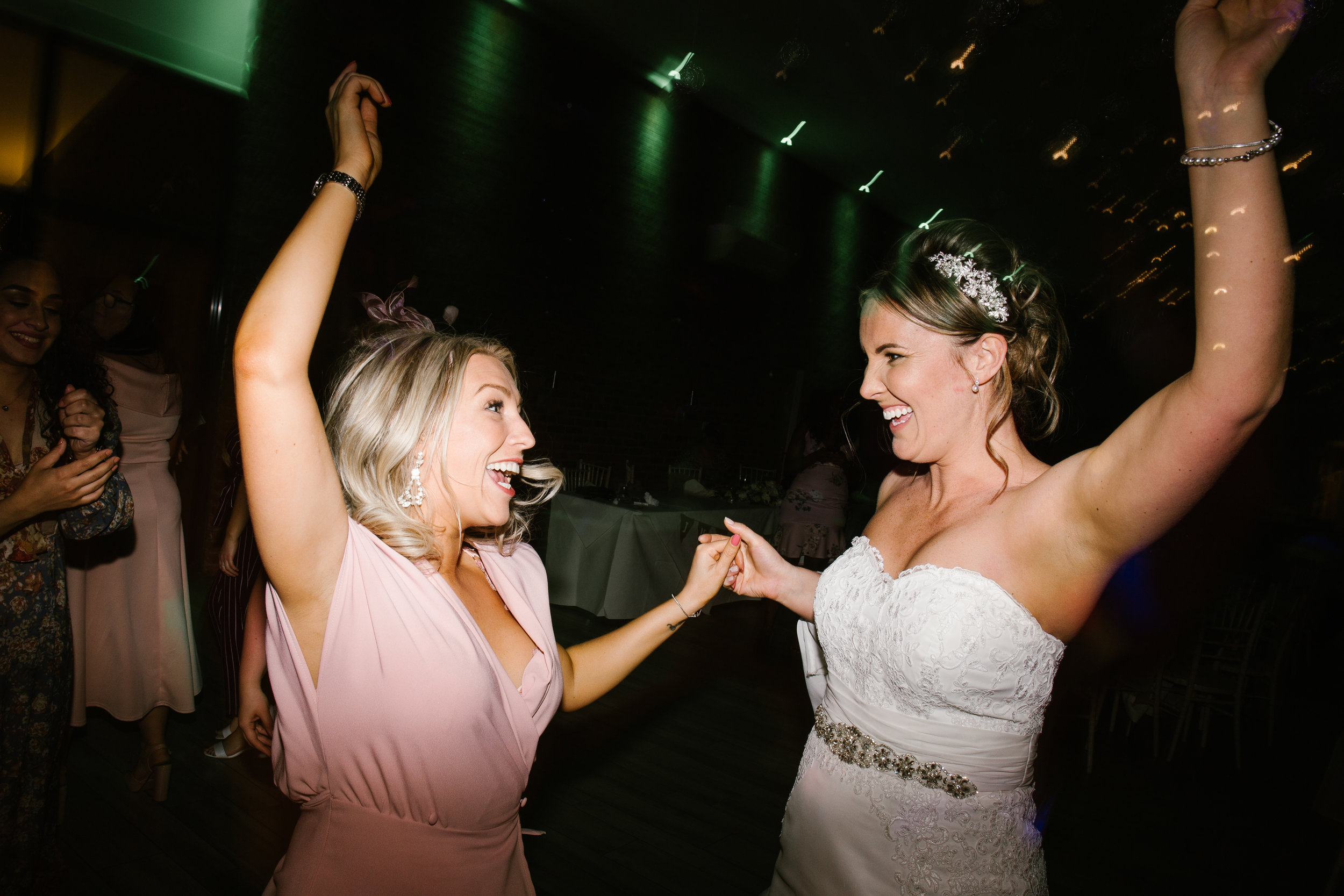 bride and wedding guest jumping up and down smiling on the dance floor