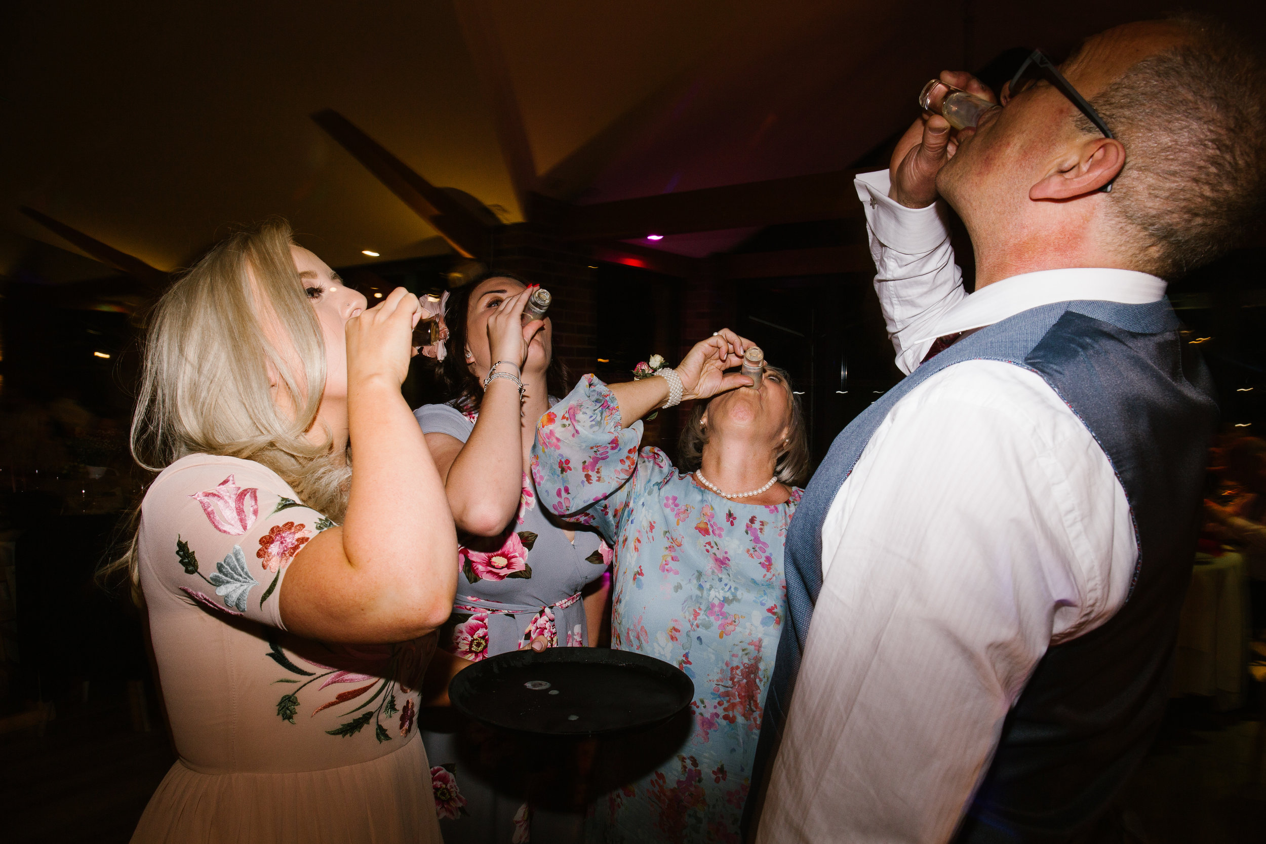 wedding guests and the mother of the bride doing shots on the dance floor at the wedding party 