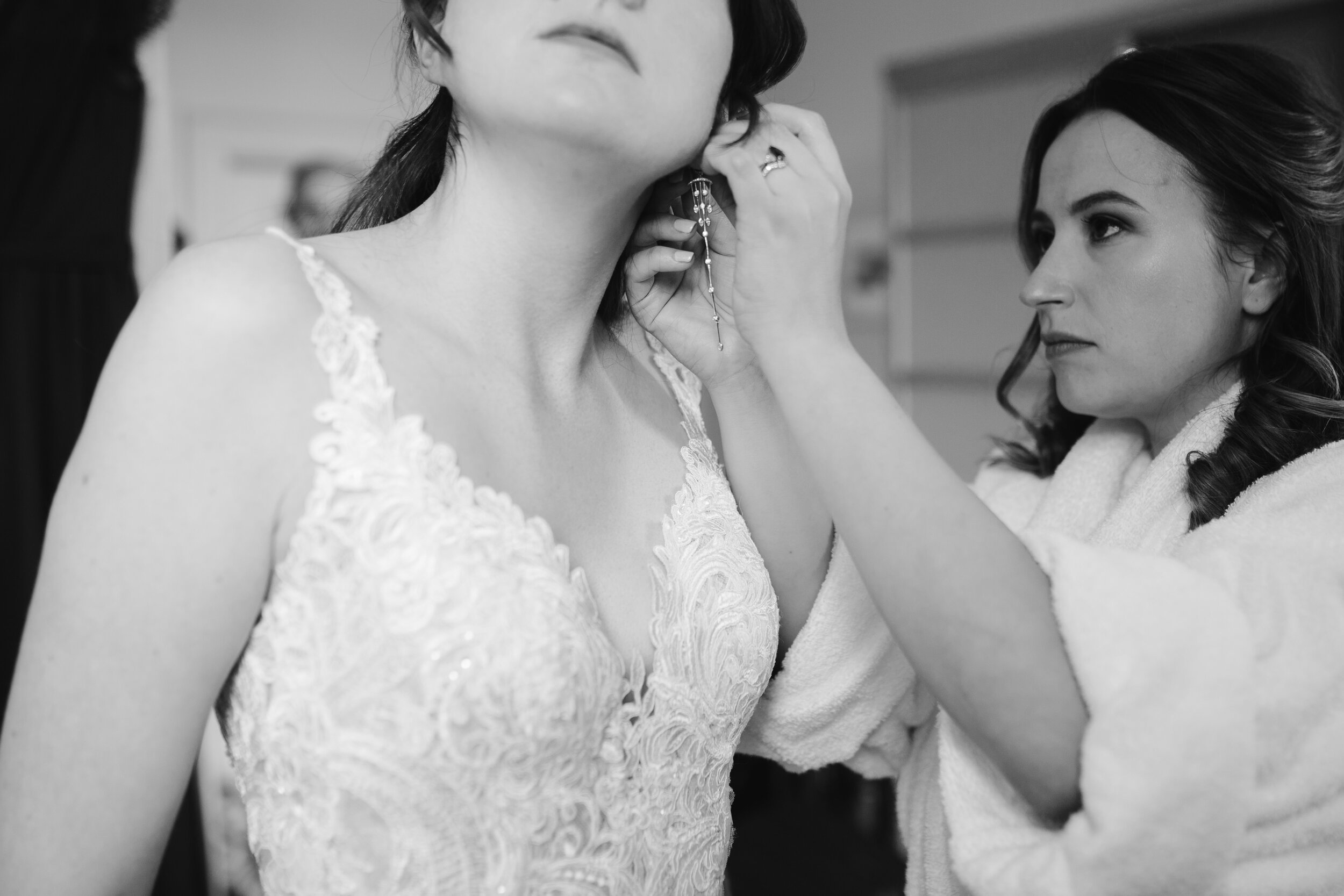 bridesmaid helping bride put in designer earrings