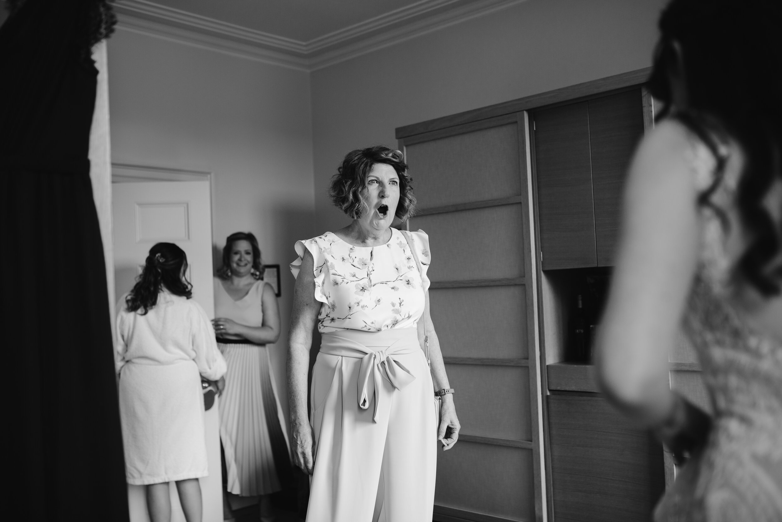 natural black and white photo of the mother of the bride seeing her daughter in her wedding dress for the first time