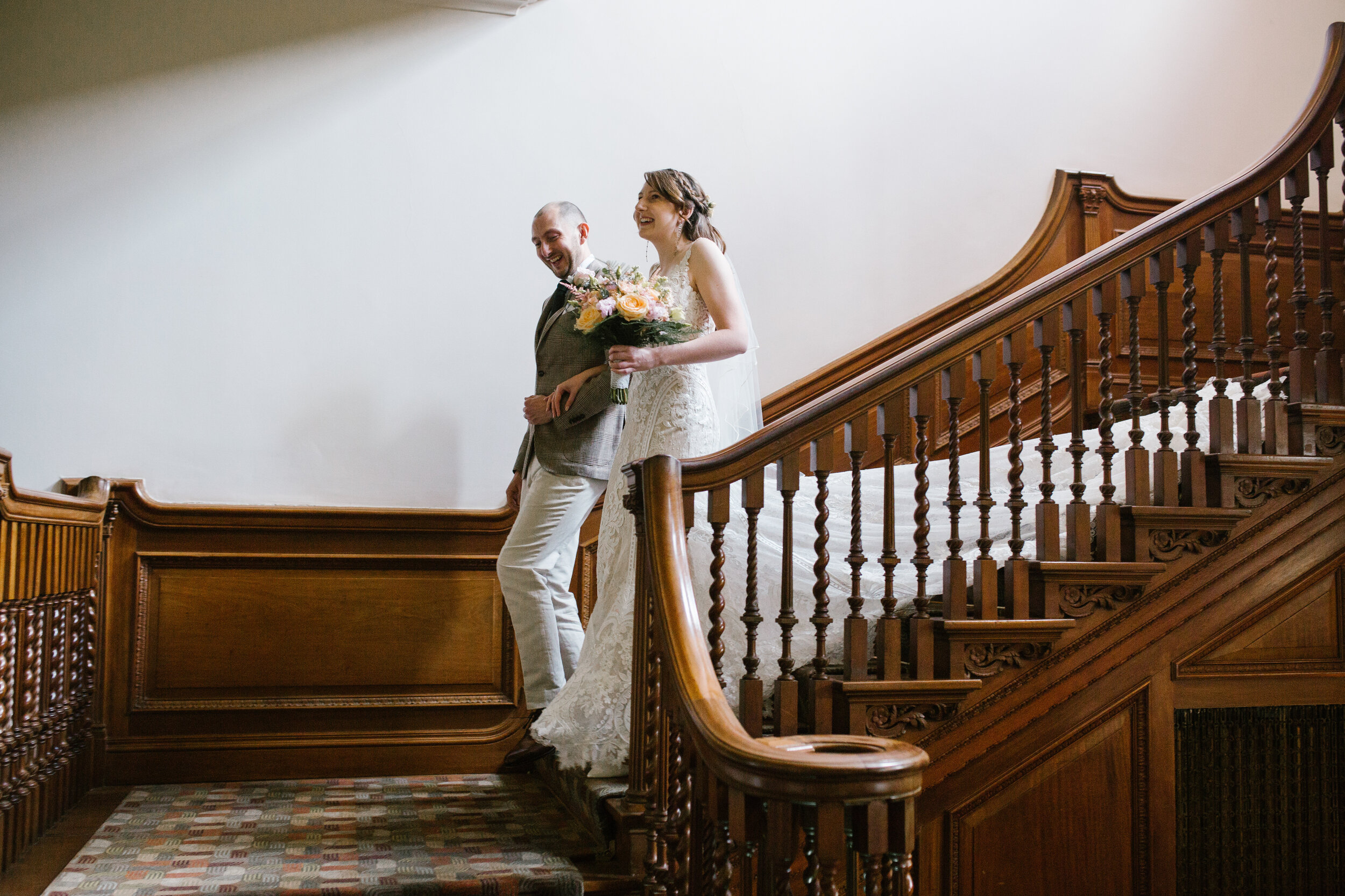bride walking down the stairs at cowley manor with her brother before getting married