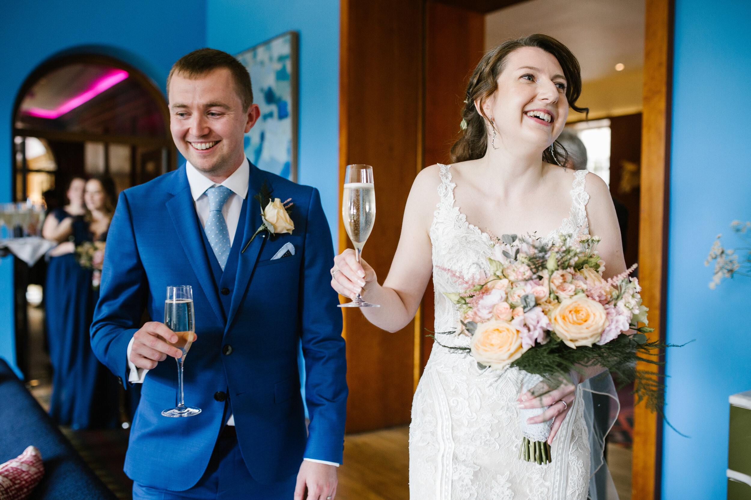 beautifully bright photo of the bride and groom drinking prosecco after just getting married at cowley manor