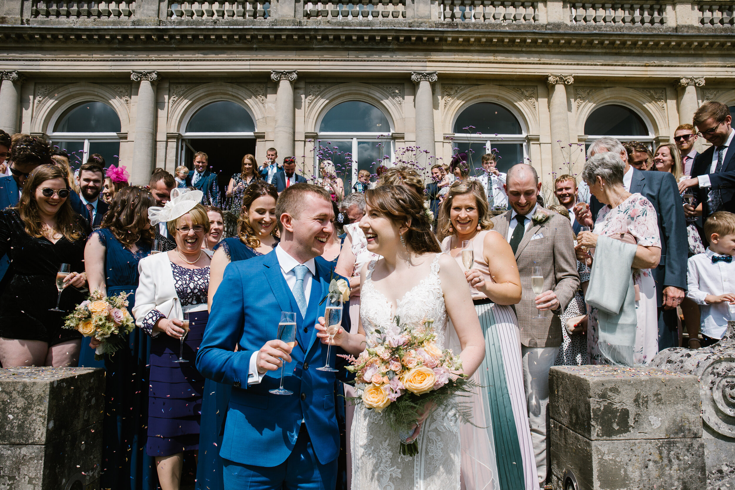 bride and groom smiling around their guests as confetti is showered over them