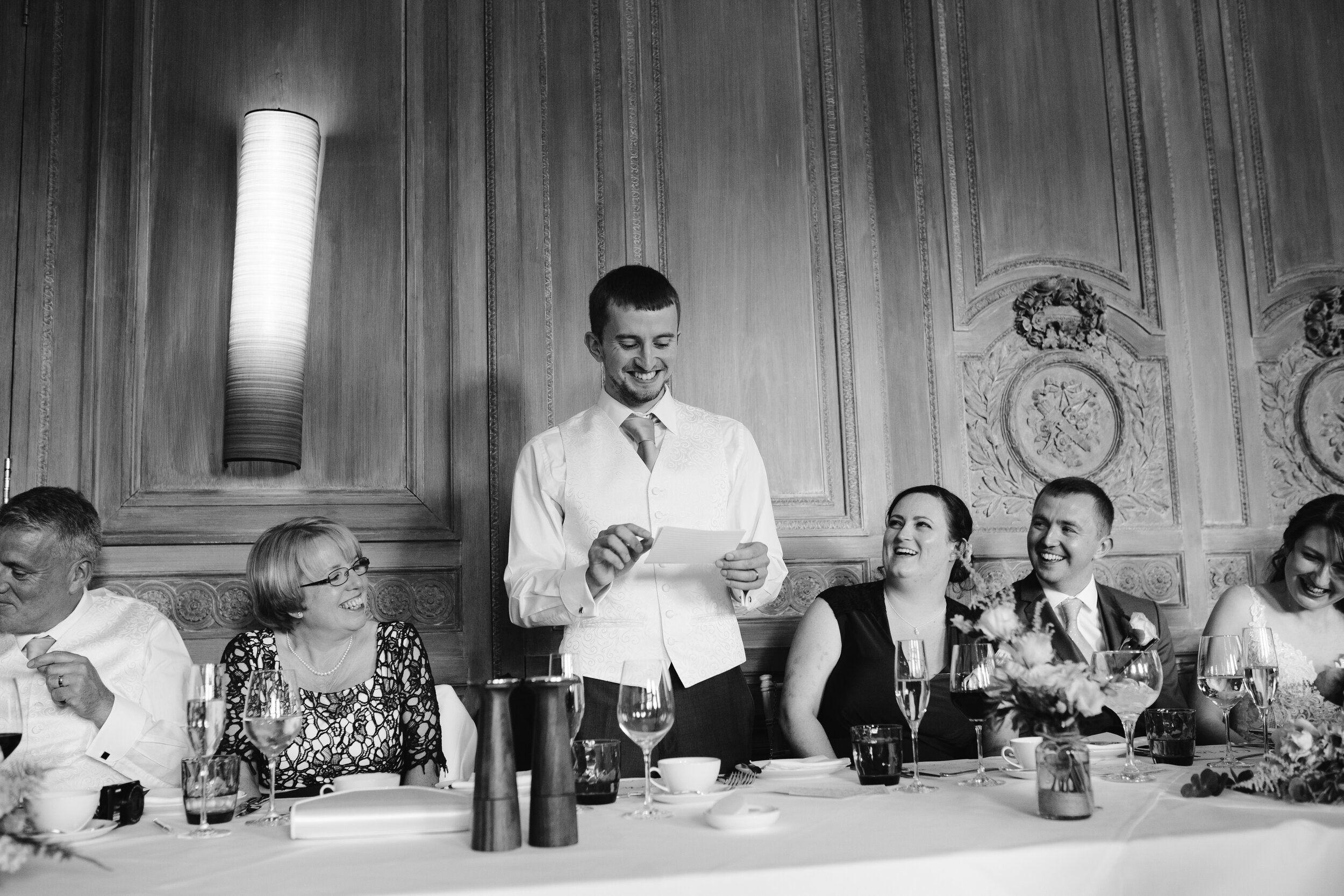 black and white photo of the best man doing his funny speech at cowley manor