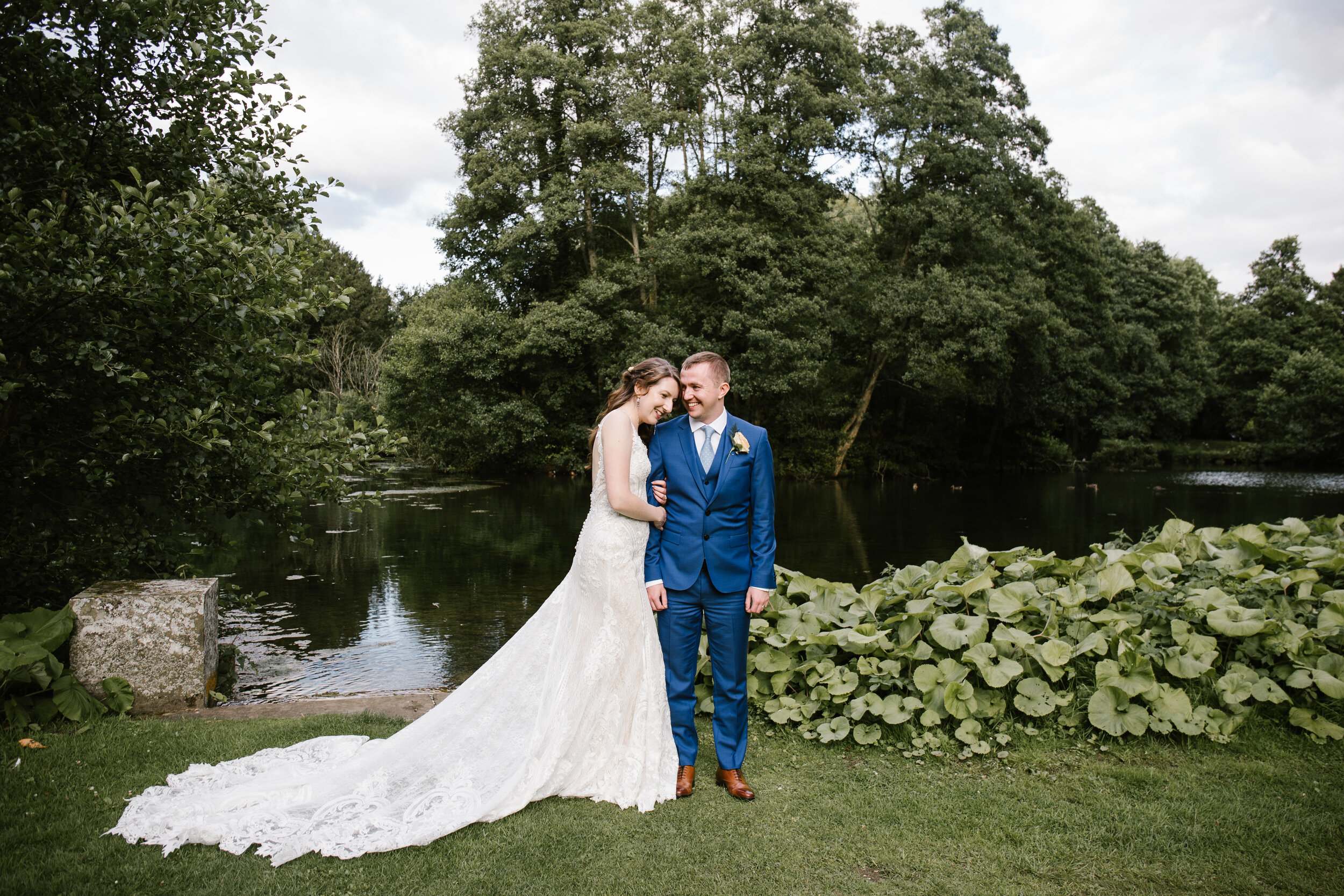 stunning portrait of bride and groom in front of the lake at cowley manor