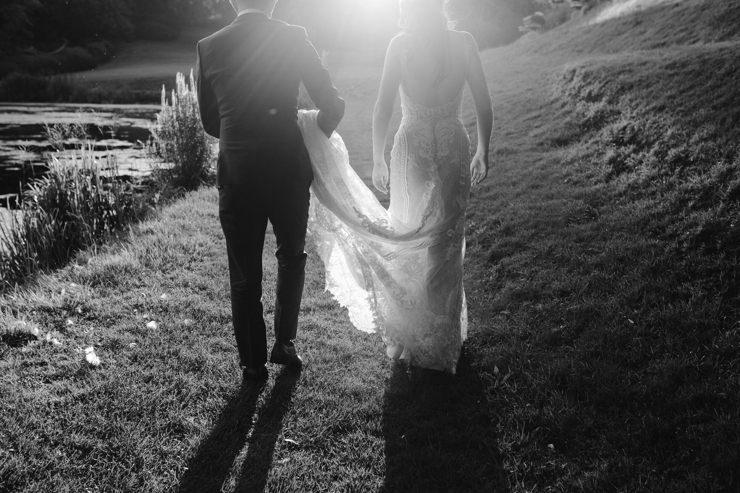 black and white photo of the groom holding the bridal gown during golden hour 