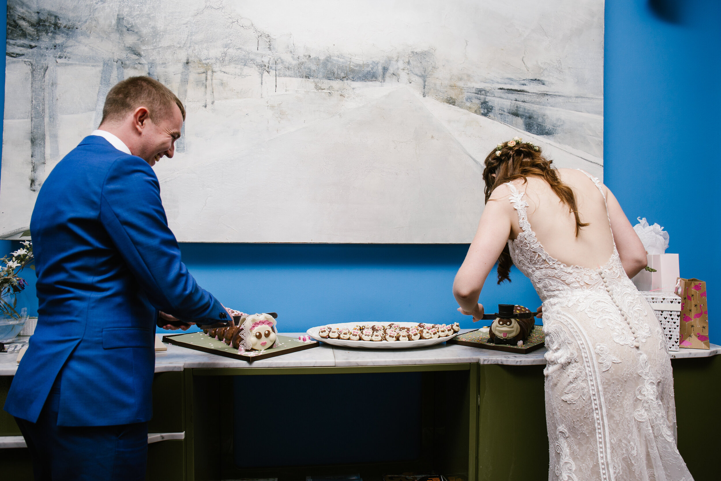 fun photo of the bride and groom cutting their wedding caterpiller cake 