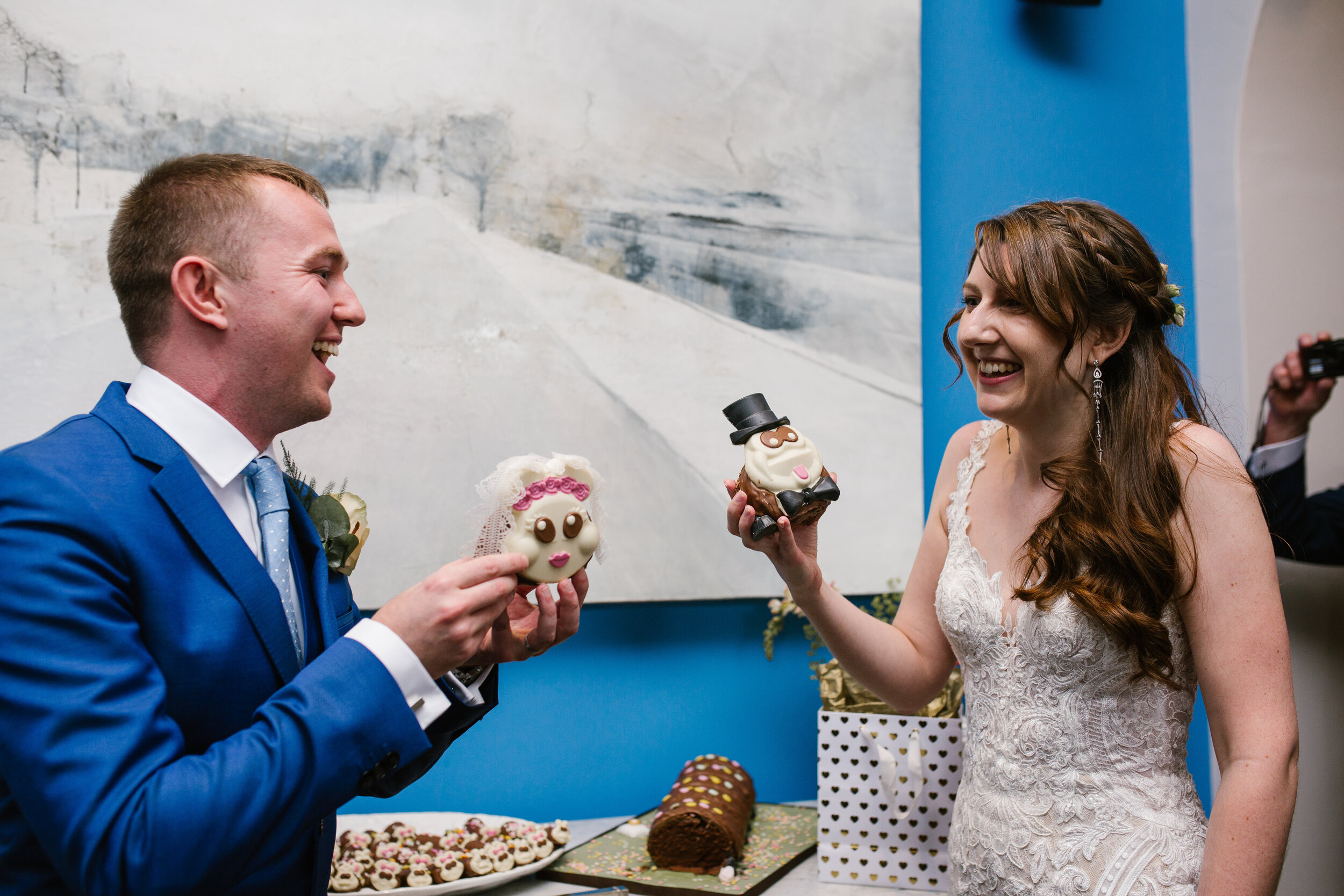 fun photo of the bride and groom after cutting the heads of their wedding caterpillar cake