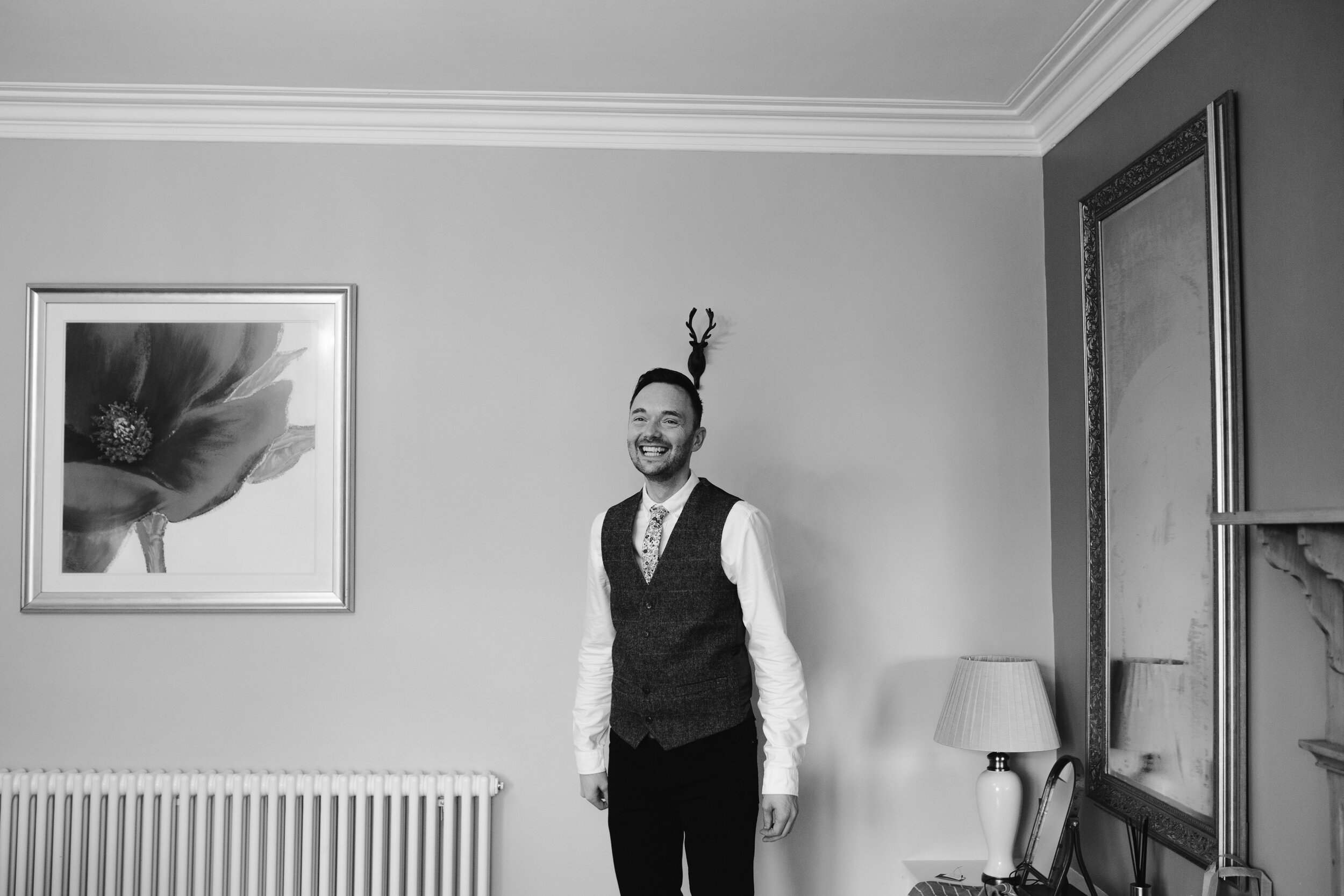 natural black and white photo of the groom smiling on the morning of his wedding day