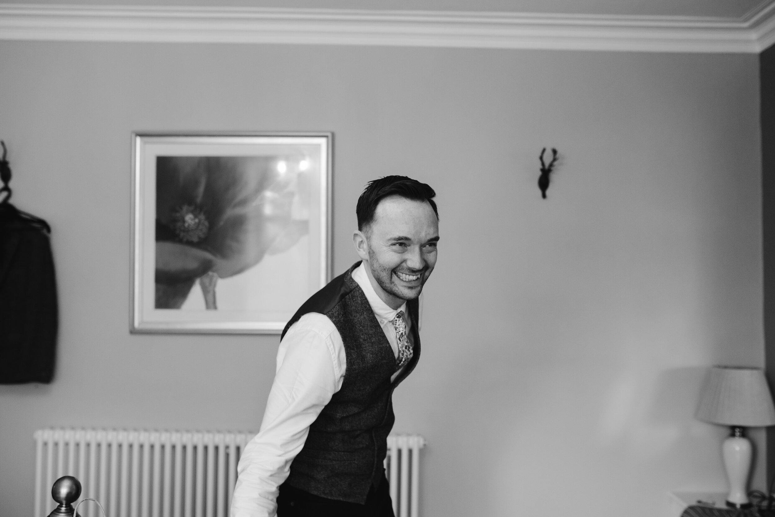 fun photo of the groom laughing on the morning of his wedding day while getting ready during groom prep