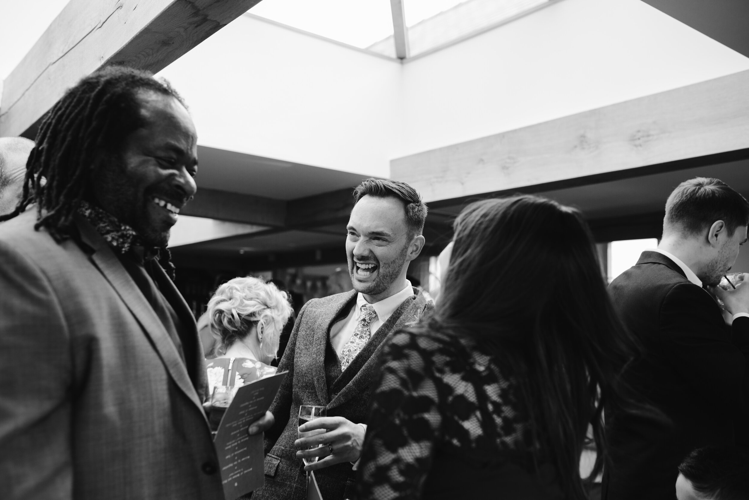 black and white photo of groom laughing with wedding guests