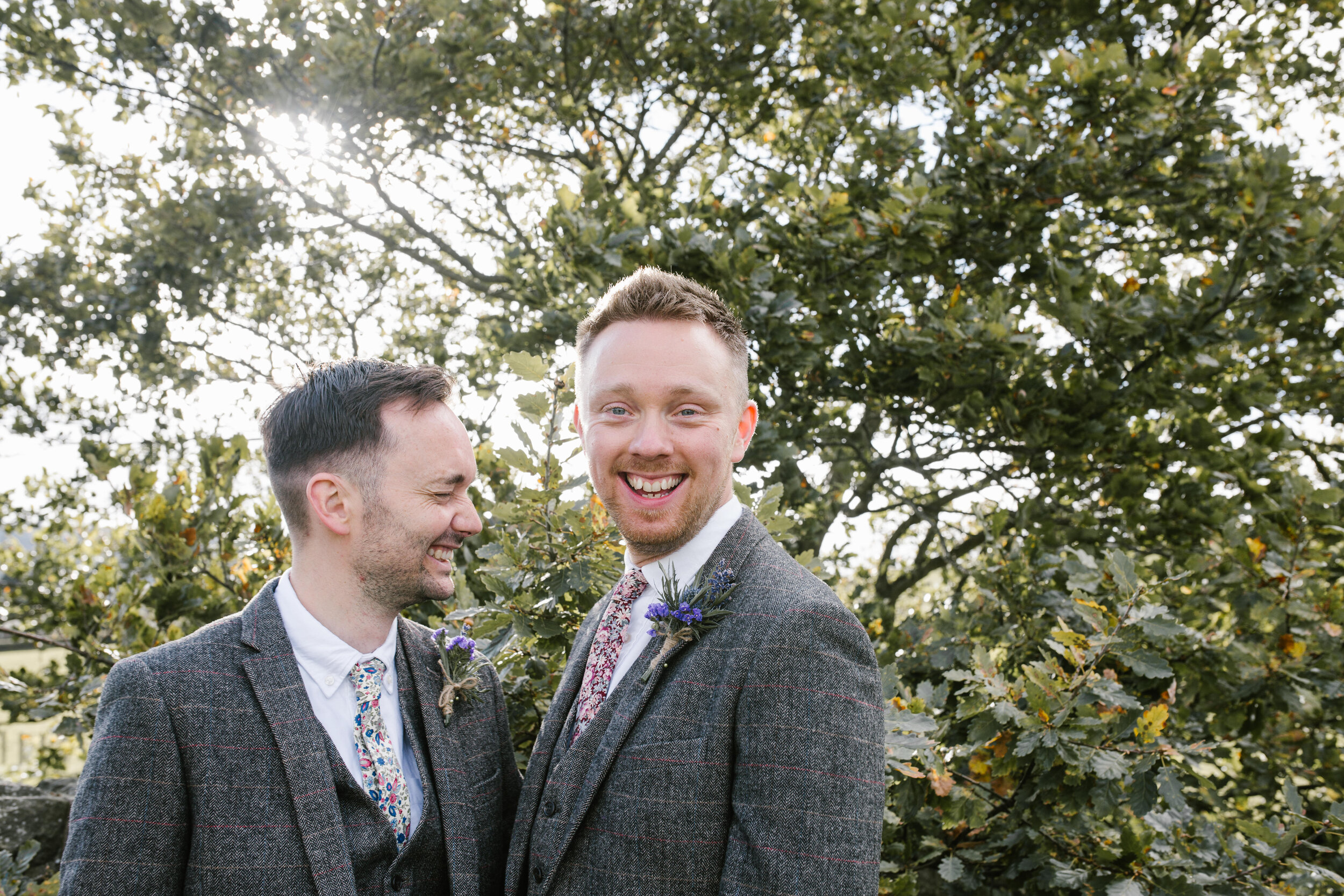 two grooms laughing together in the golden light