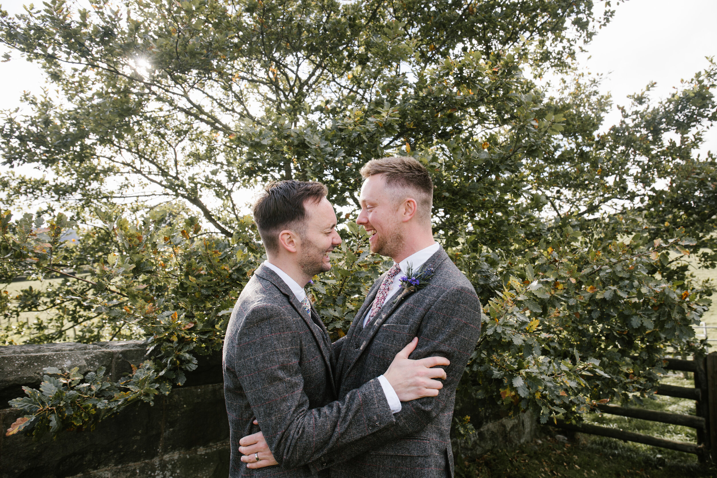 natural photo of grooms laughinmg together at their wedding at tower hill barns
