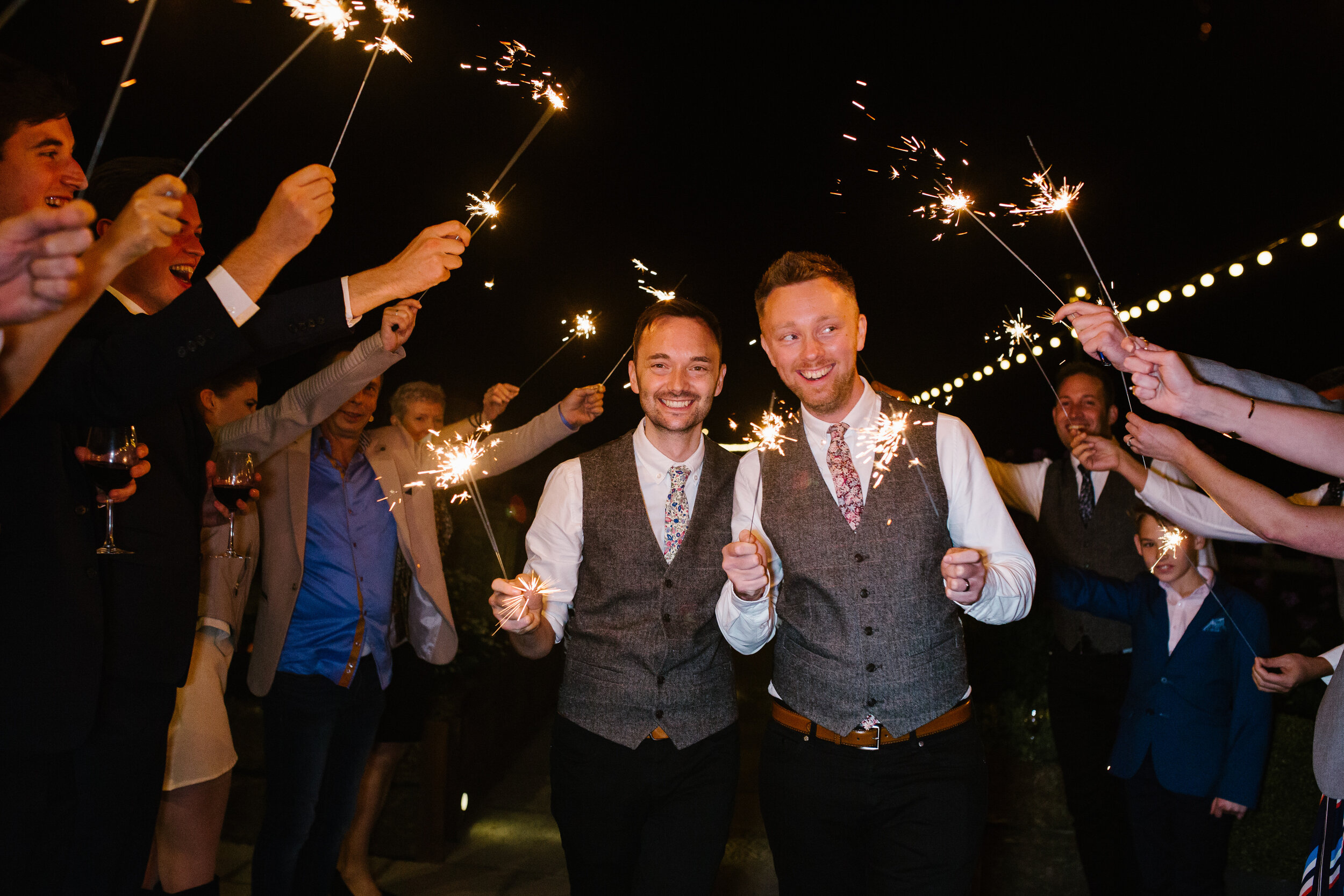 grooms walk through an aisle of sparklers