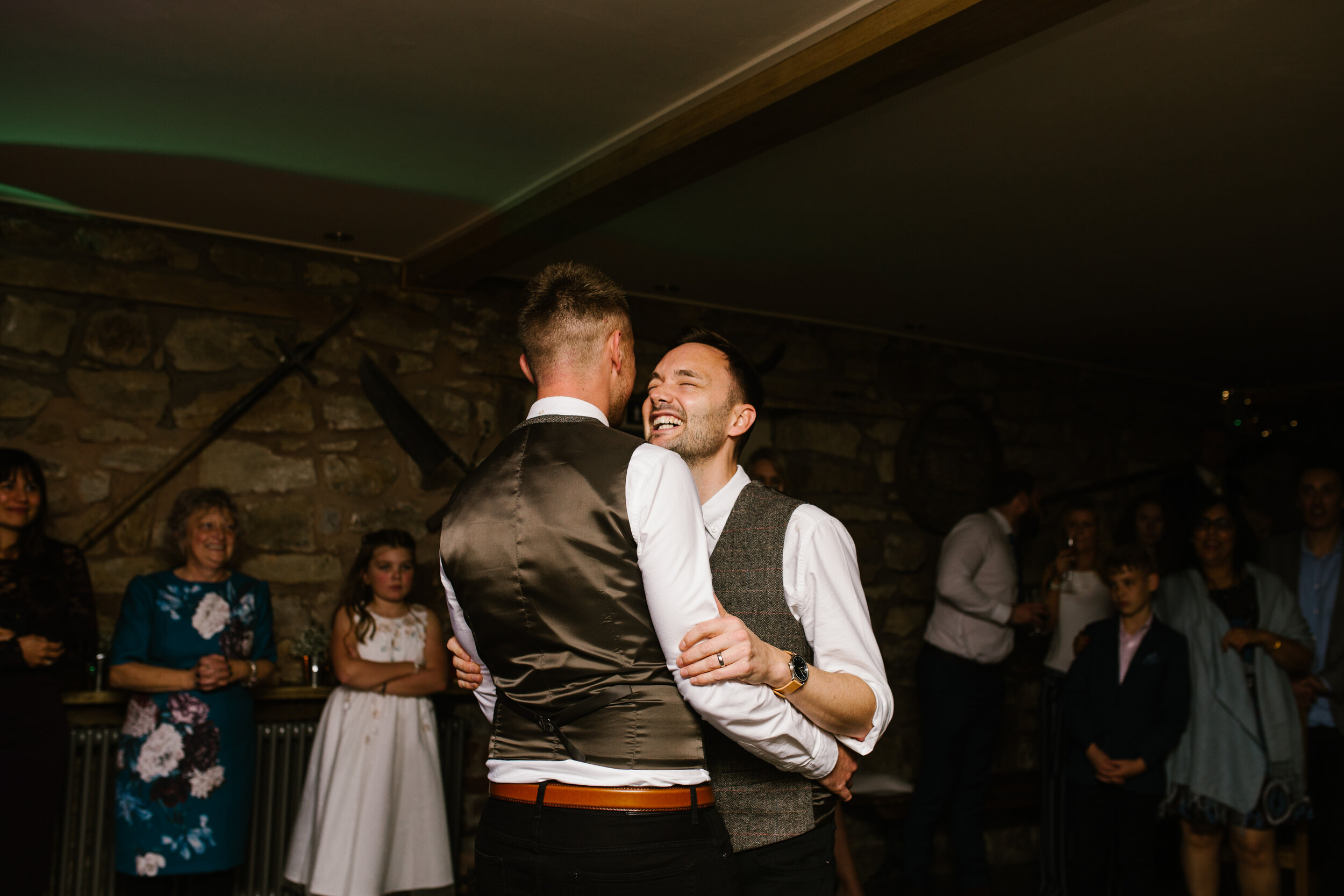 grooms smiling and laughing together during their first dance