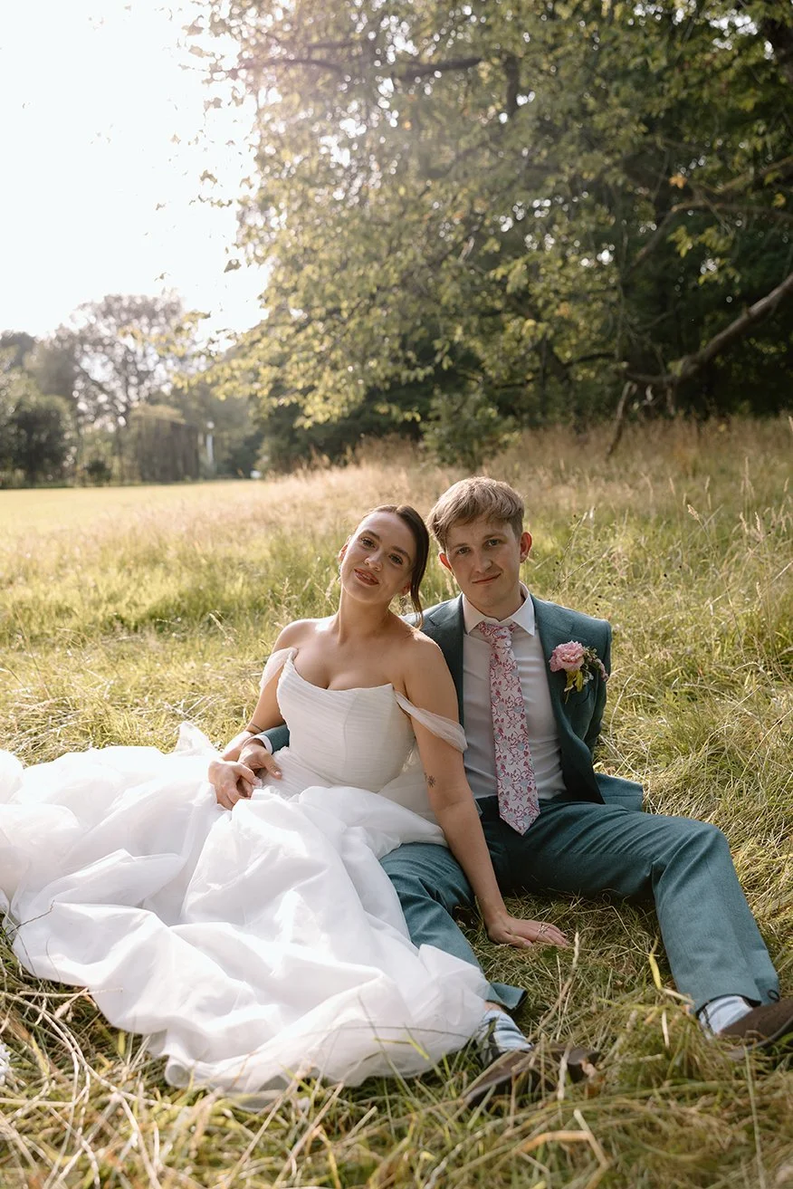 Bride and groom sat outside Sefton Park Palm house on their wedding day